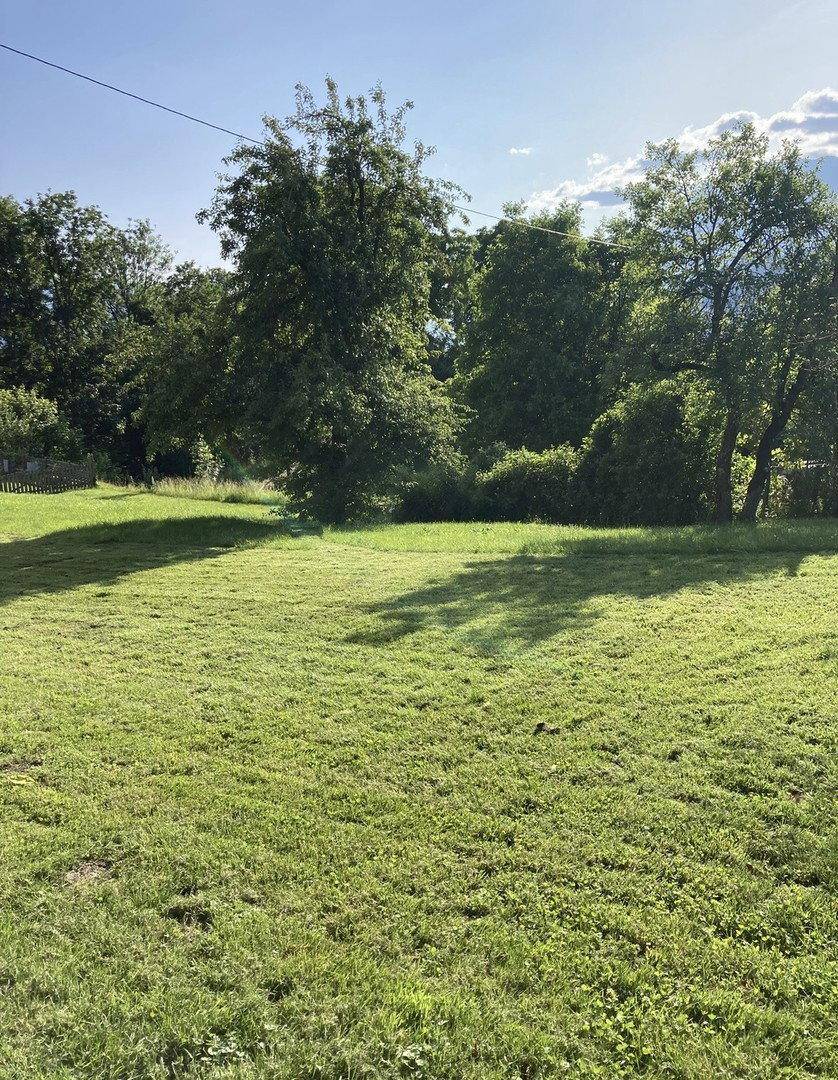 Weitläufige, frisch gemähte Rasenfläche umgeben von Bäumen an einem sonnigen Tag.
