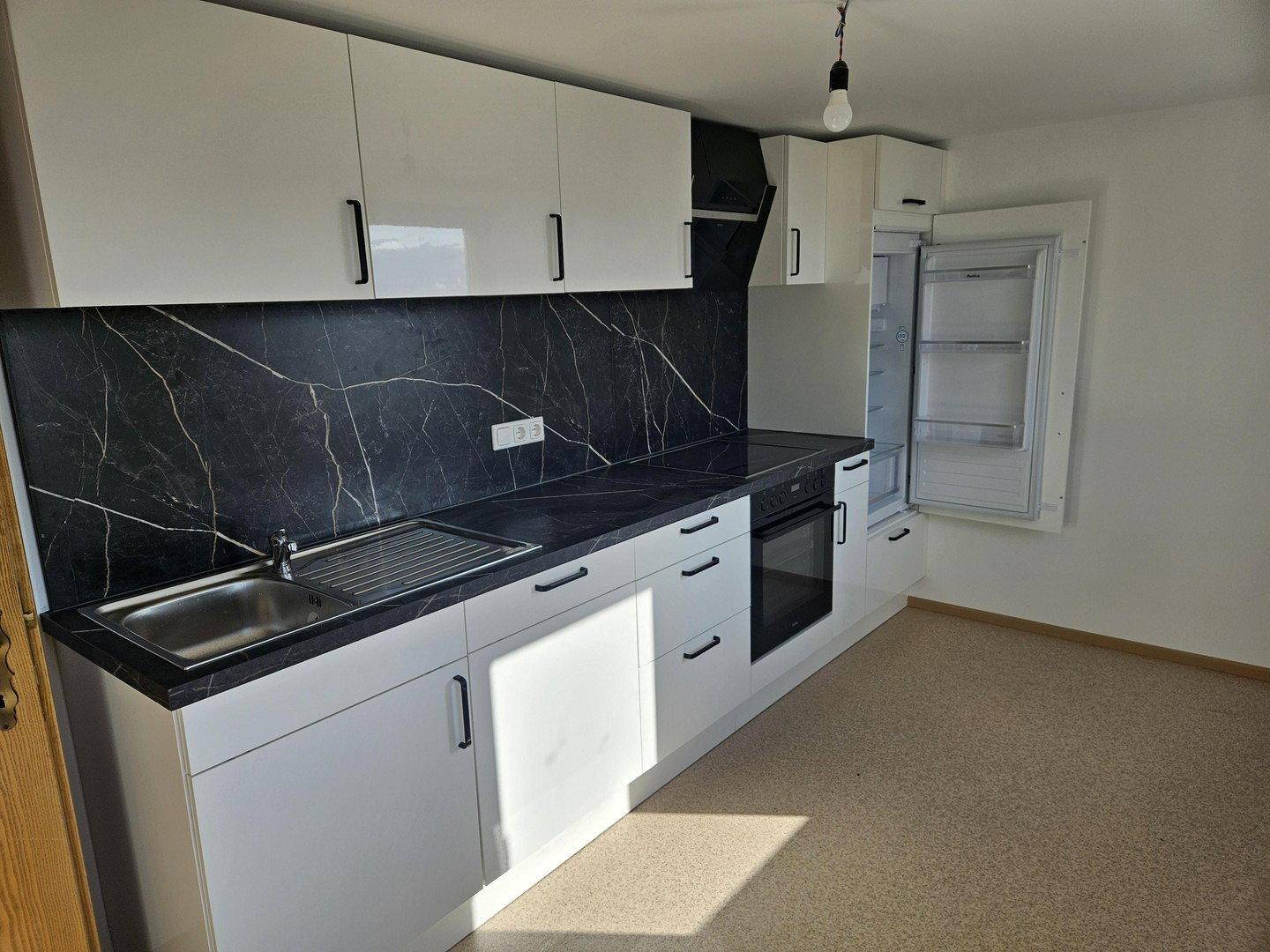 Moderne Einbauküche mit weißen Hochglanzfronten, integriertem Backofen und Kühlschrank.