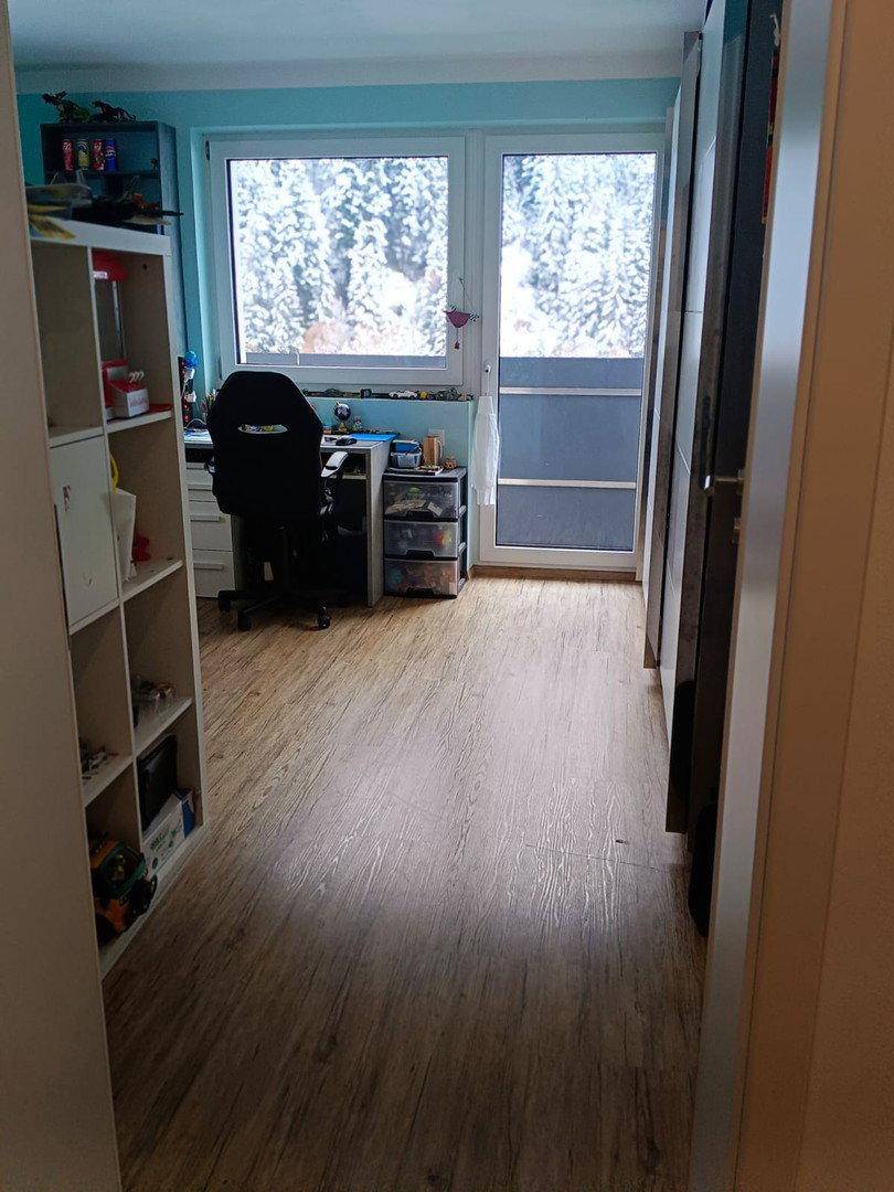 Heller Flur mit Laminatboden, der zu einem Zimmer mit Blick ins Grüne führt.