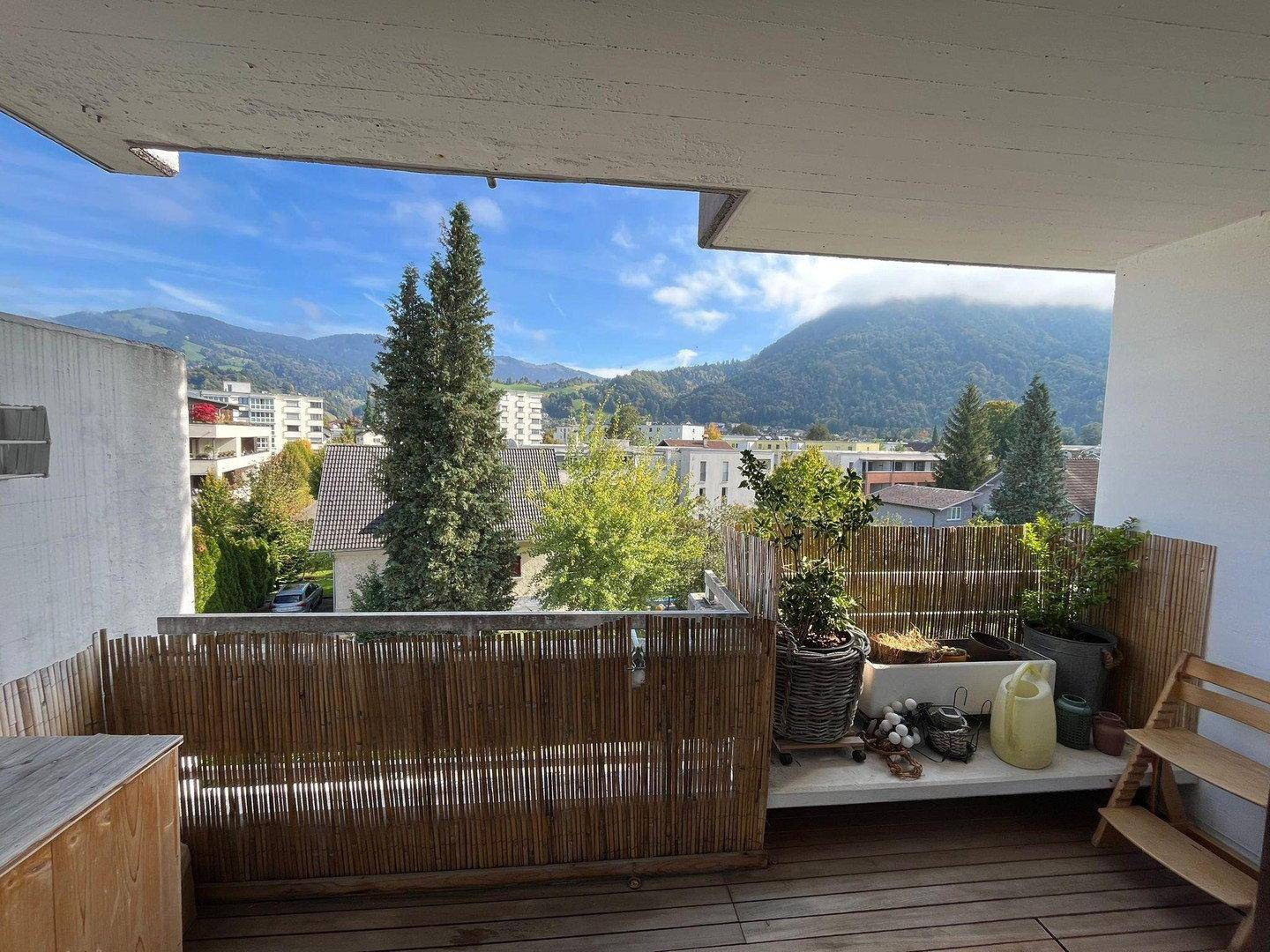 Geräumiger Balkon mit Holzboden und Bambuszaun, bietet einen weiten Blick auf die Berge und die Stadt.
