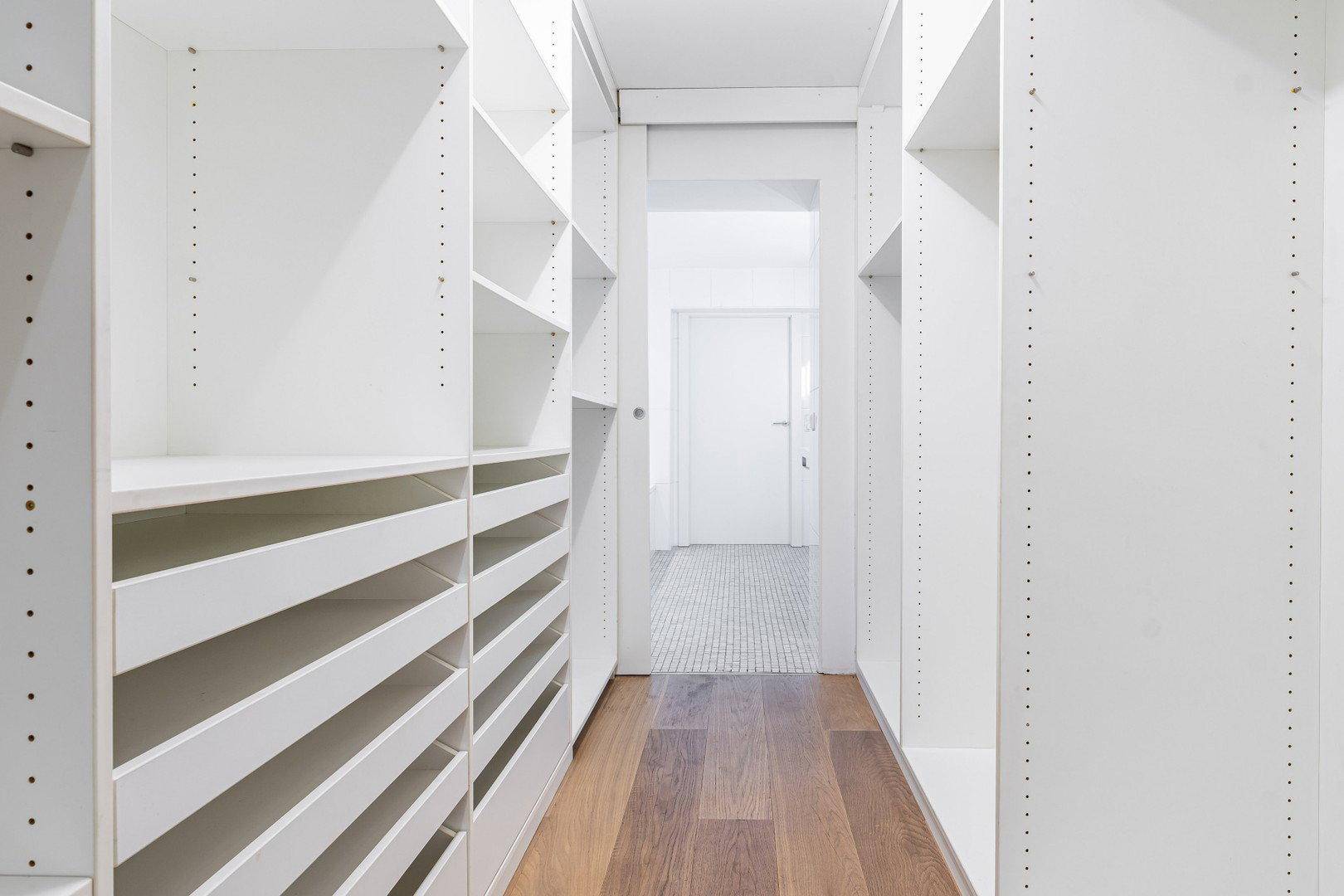 Geräumiger begehbarer Kleiderschrank mit vielen Regalen und Schubladen für Organisation.