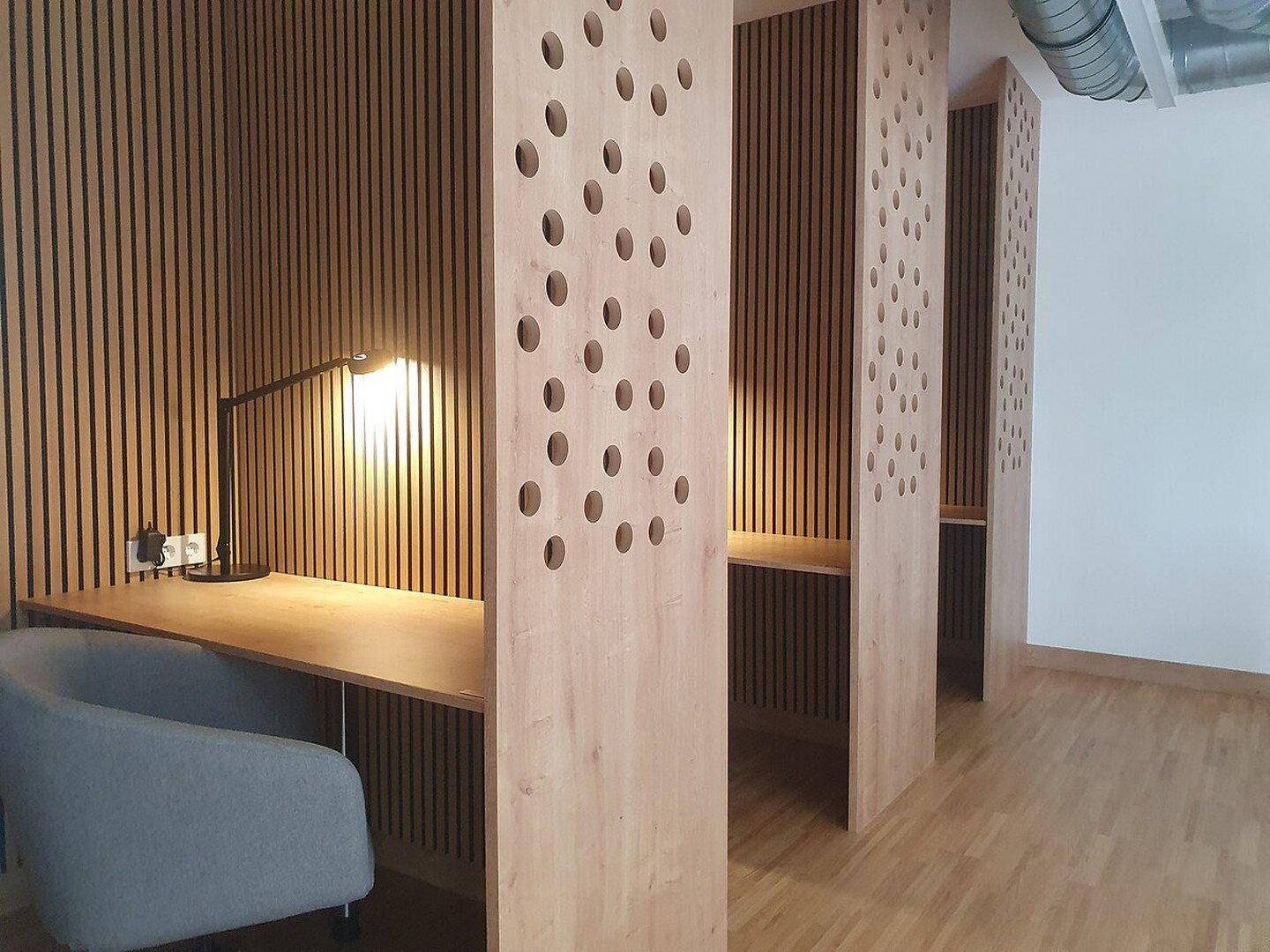 Moderner Co-Working-Bereich mit individuellen Holzkabinen, Schreibtischen und Holzlamellenwänden.