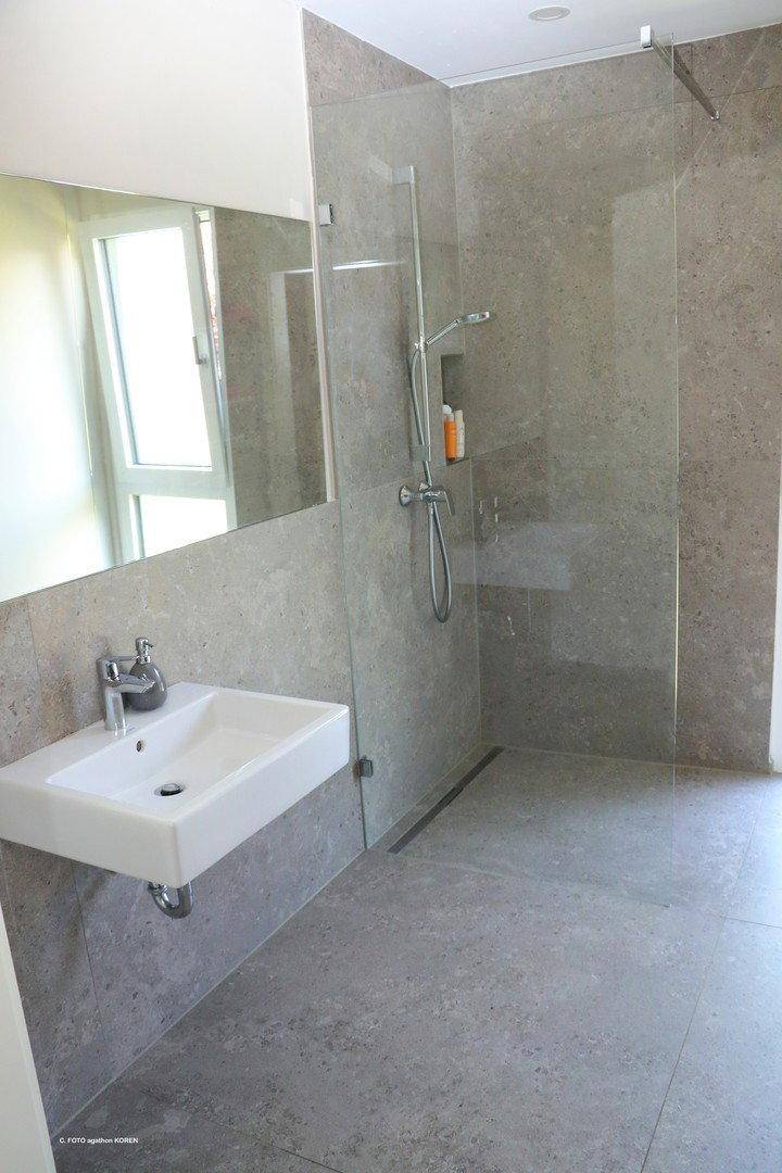 Modernes Badezimmer mit ebenerdiger Dusche, Glasabtrennung und großem Spiegel.