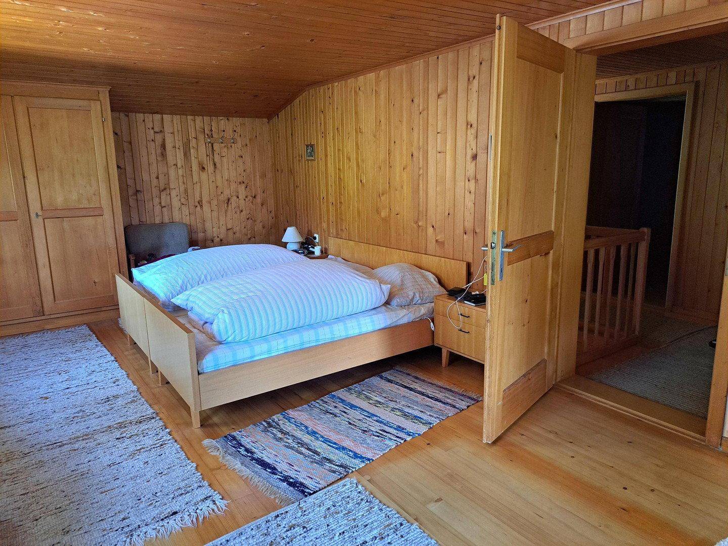 Geräumiges Schlafzimmer mit Doppelbett, Holzvertäfelung und integriertem Kleiderschrank.
