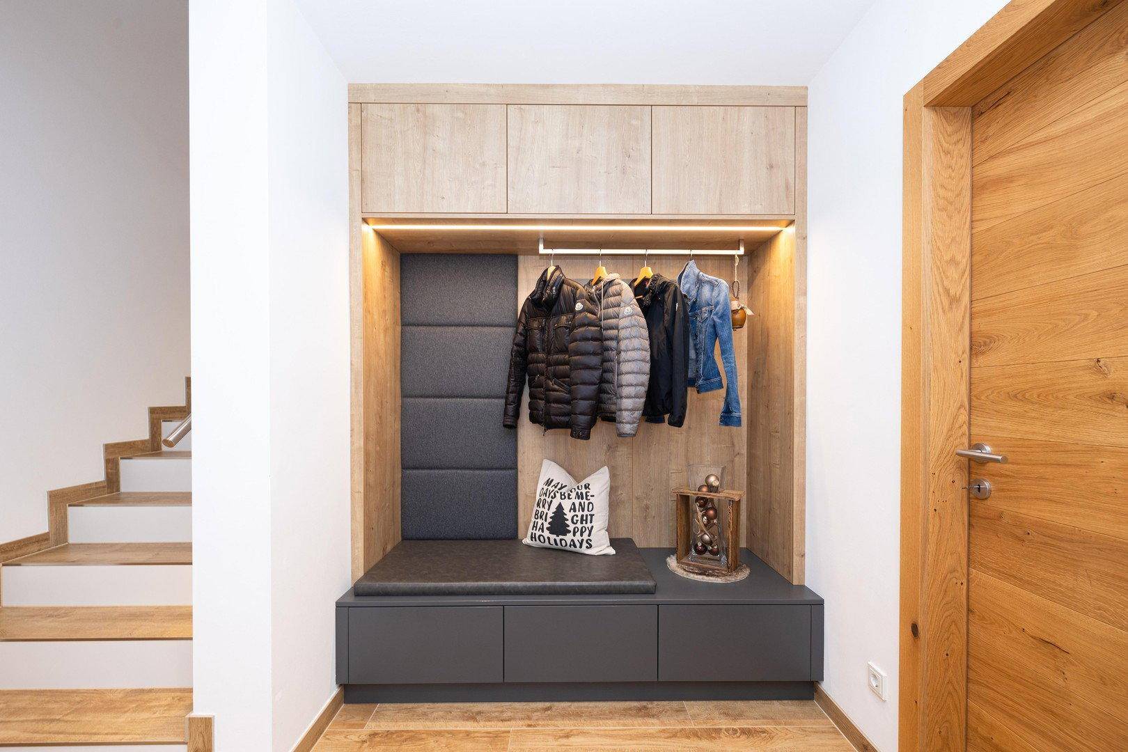 Moderner Eingangsbereich mit integrierter Garderobe, Sitzbank und Holztreppe.