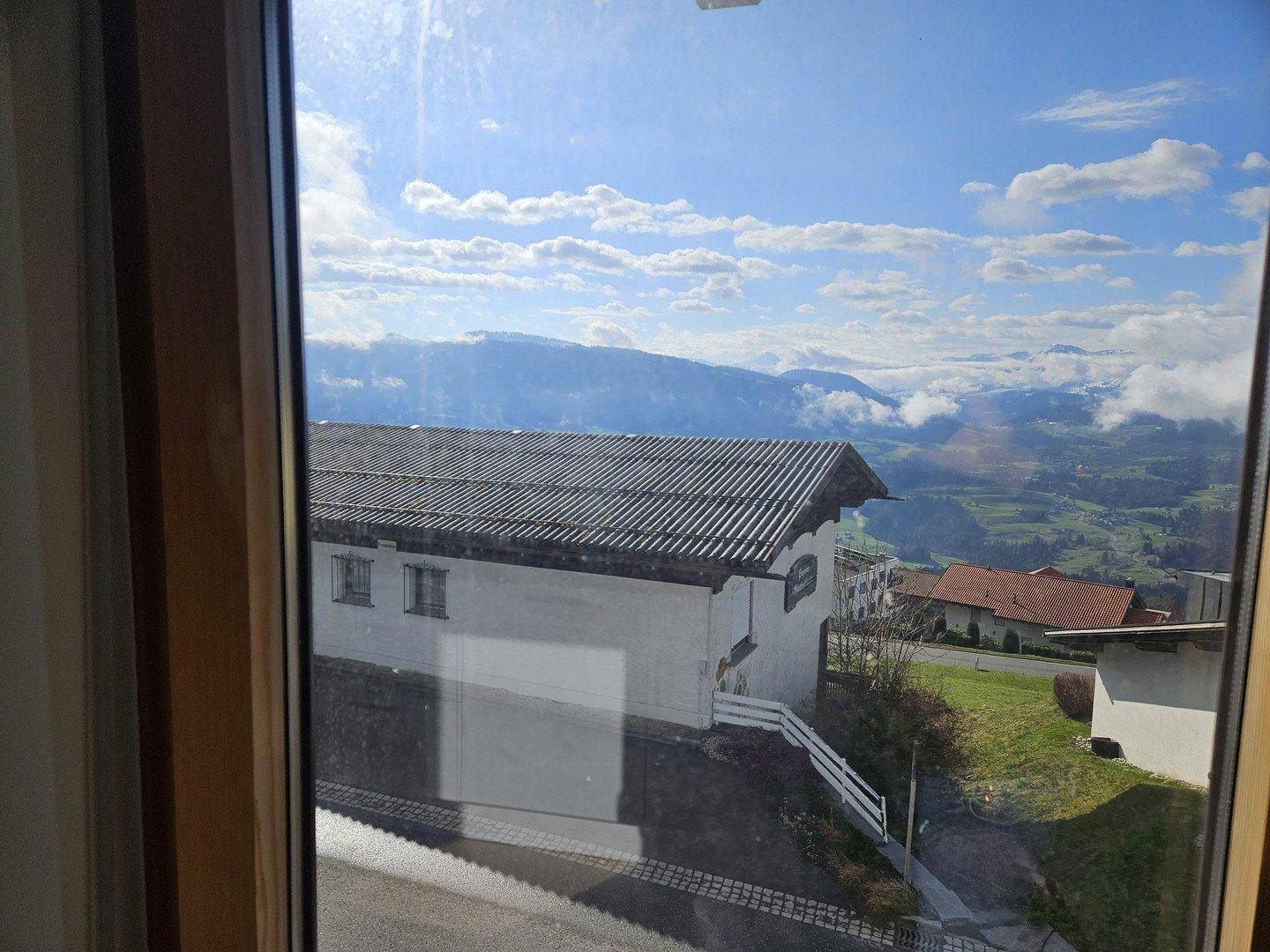 Panoramablick aus dem Fenster auf die umliegende Berglandschaft und grüne Hügel.