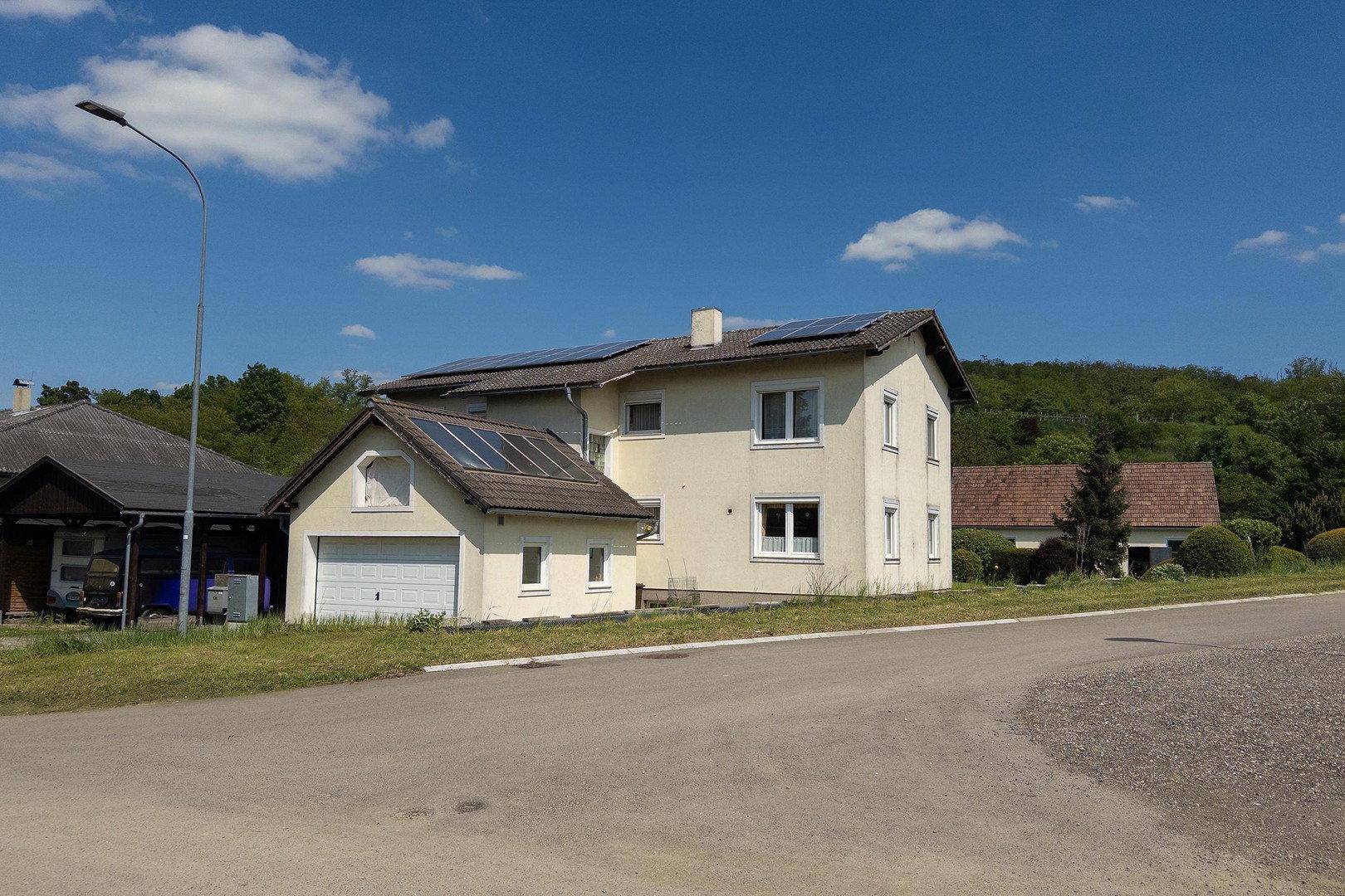Ansicht des Hauses von der Straße mit Garage und Solaranlage auf dem Dach.