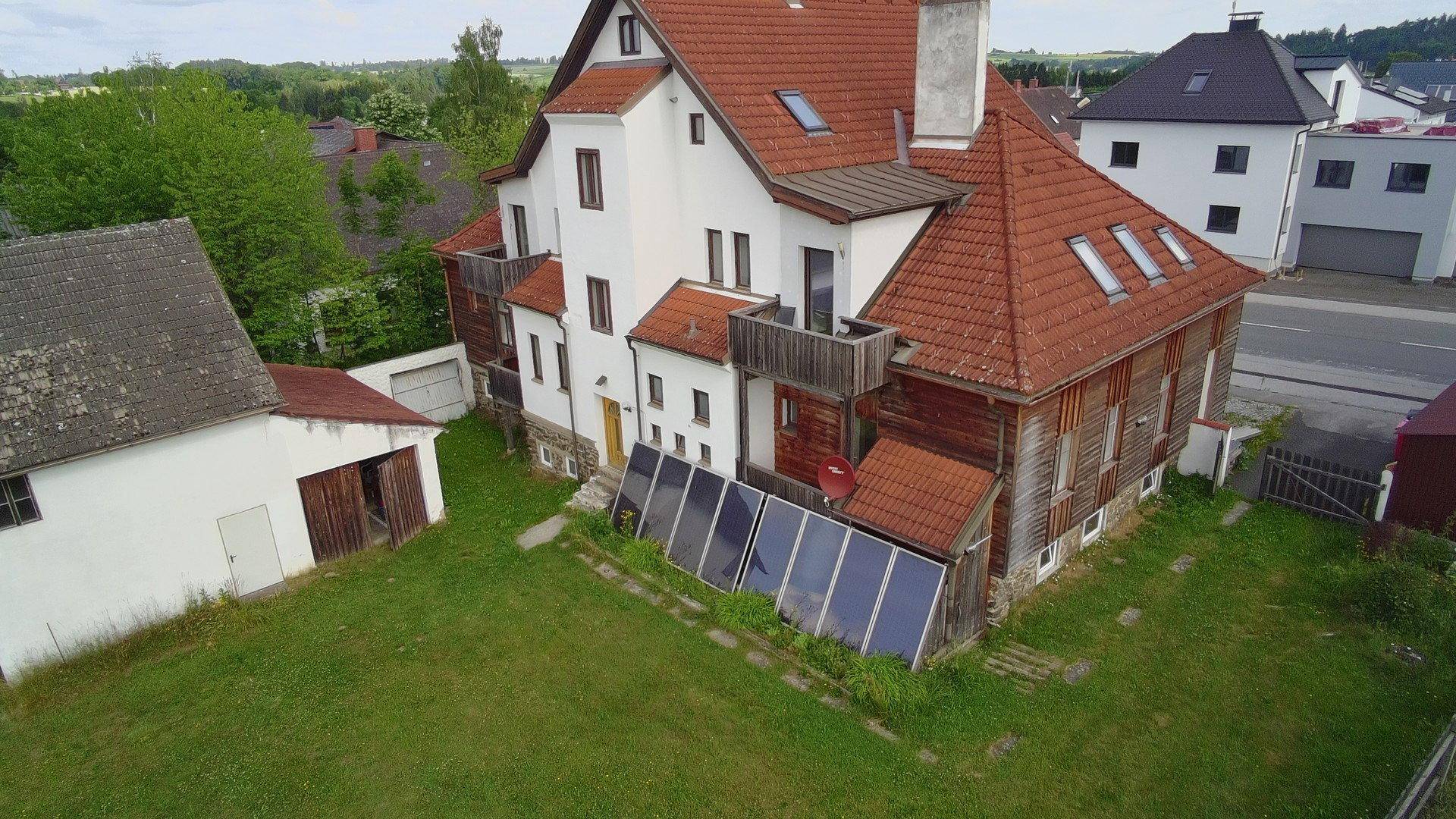 Rückansicht des Gebäudes mit Solarpaneelen auf dem Dach und großem Gartenbereich.