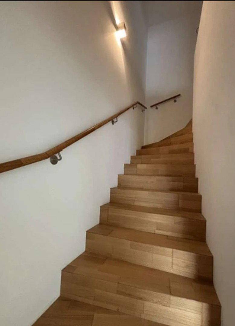 Elegante Holztreppe mit passendem Handlauf, die in die obere Etage führt.