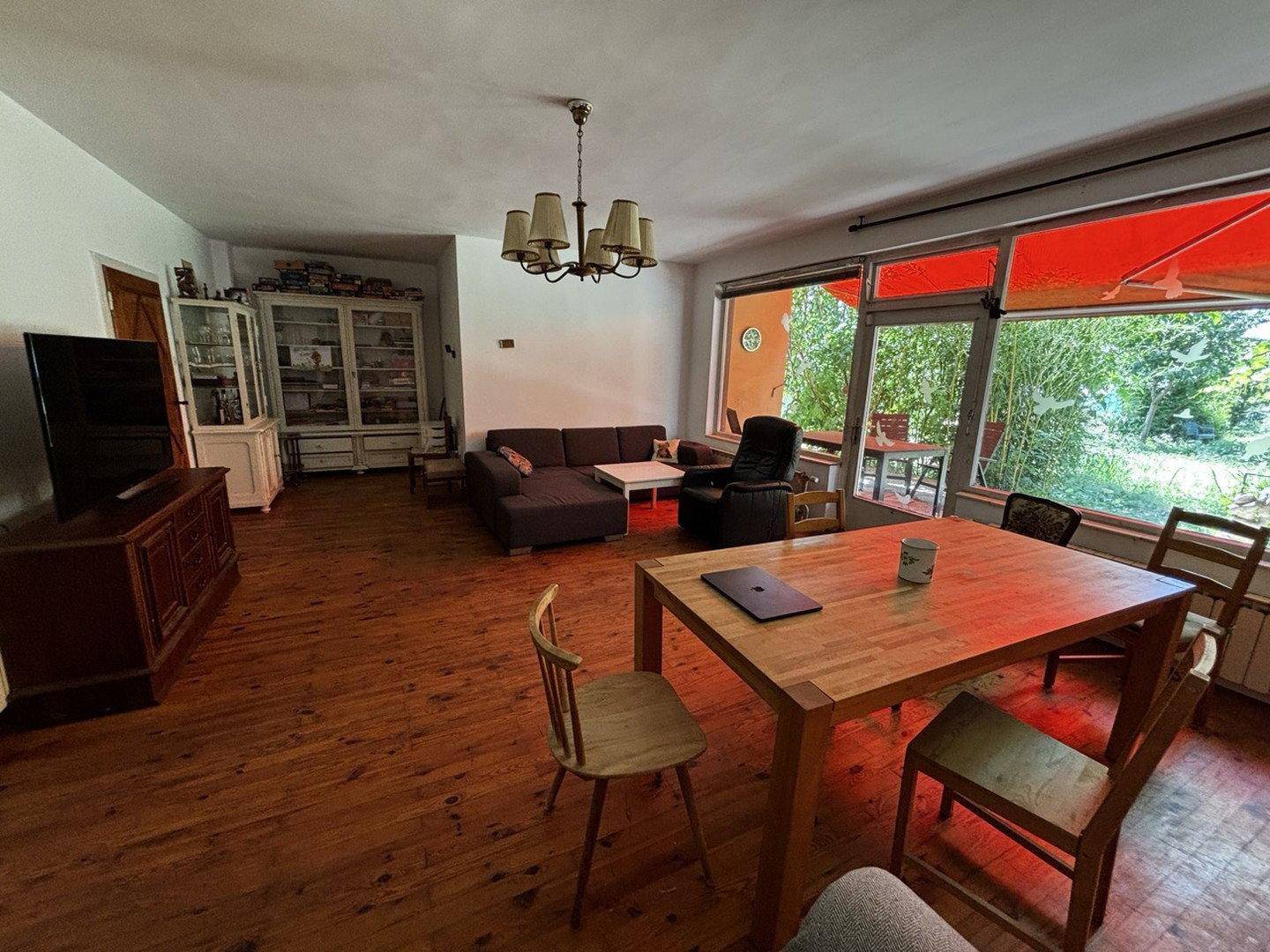 Offener Wohn- und Essbereich mit Holzboden, Esstisch und Zugang zur überdachten Terrasse.