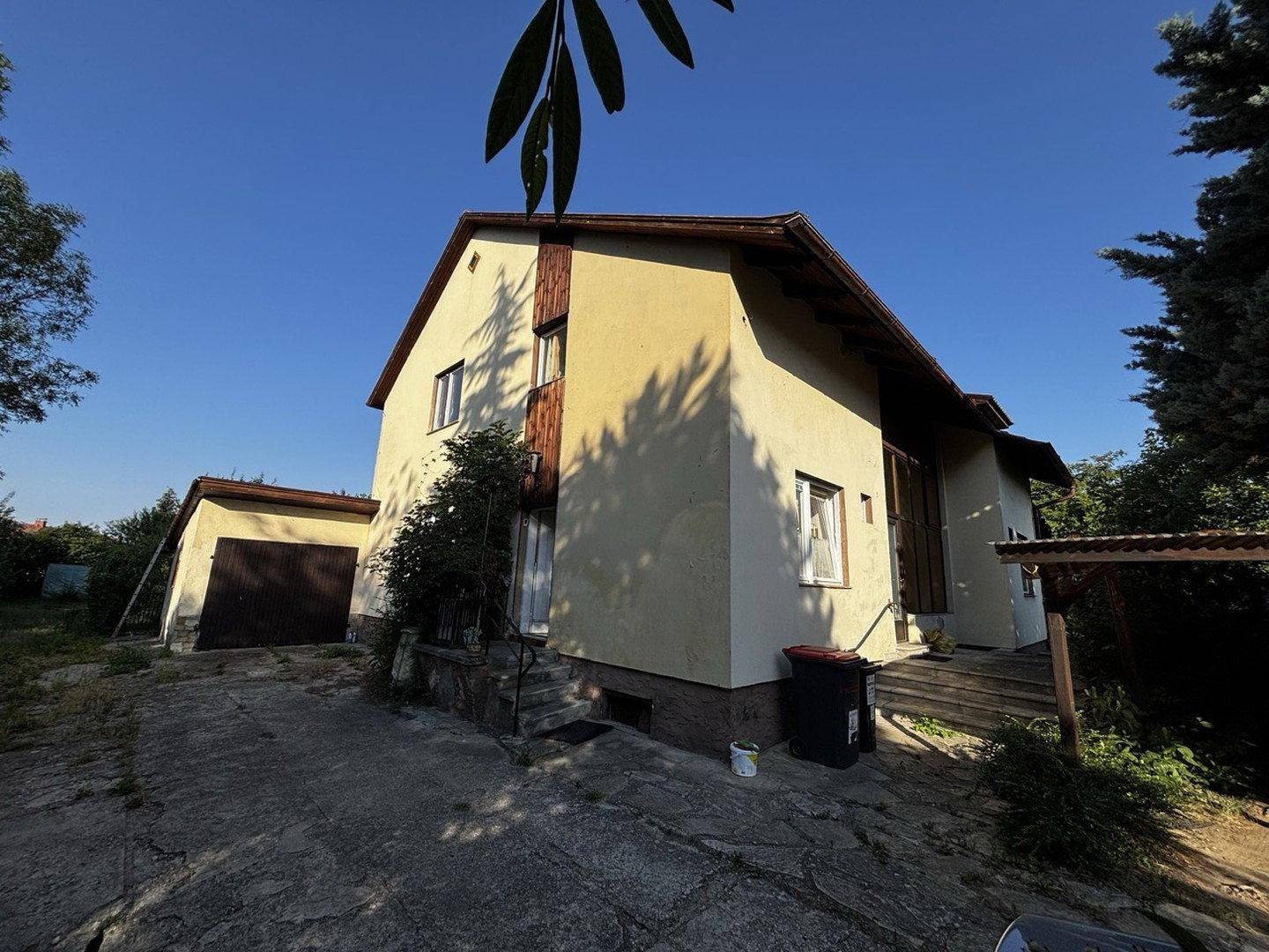 Seitenansicht des Hauses mit Zufahrt zur Garage und einfacher Fassadengestaltung.