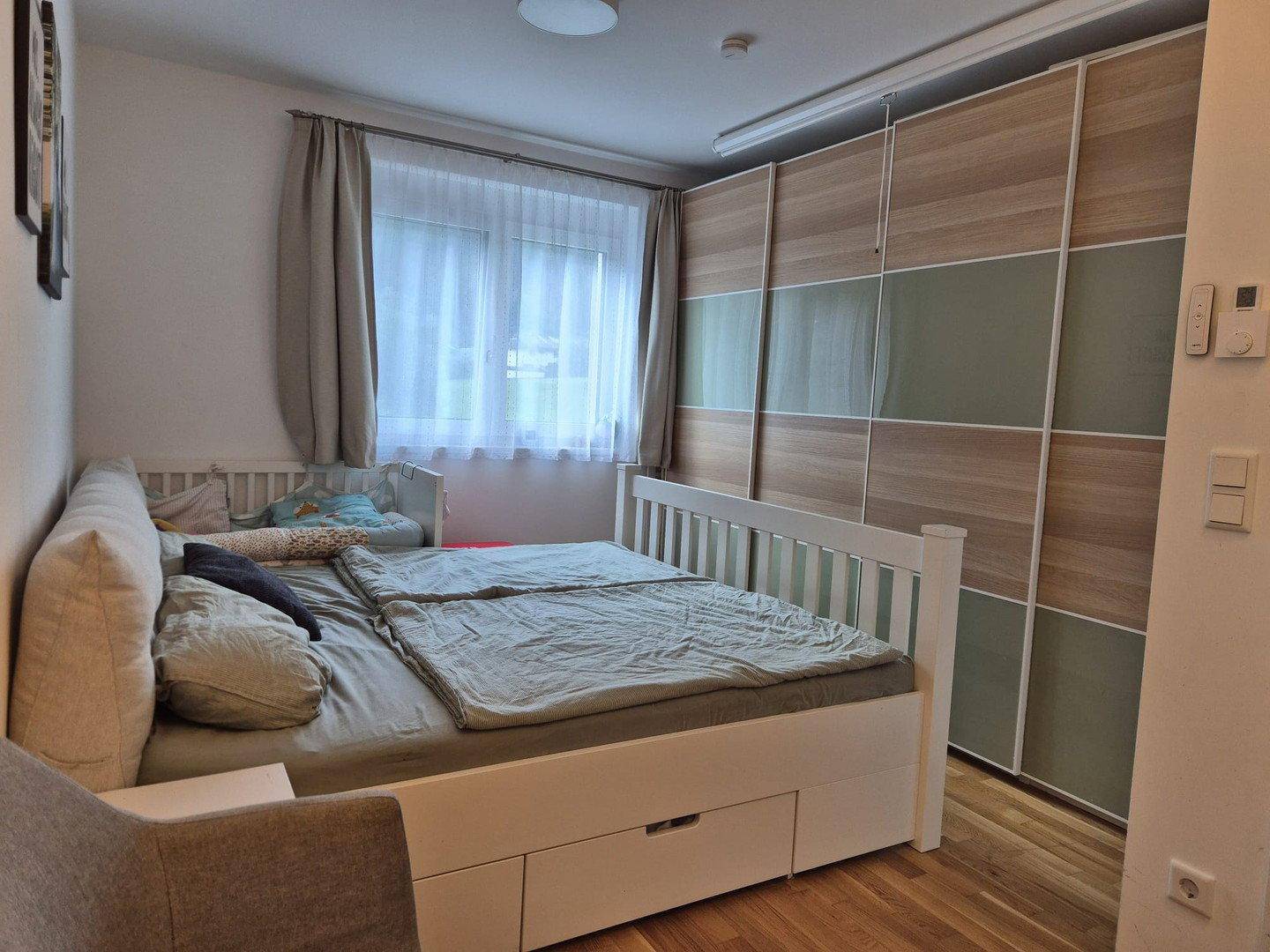 Schlafzimmer mit Doppelbett, integrierten Schubladen und großem Kleiderschrank.