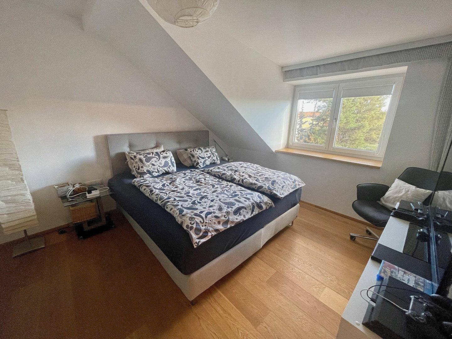 Helles Schlafzimmer mit Doppelbett, Holzboden und Dachschräge, bietet eine gemütliche Atmosphäre.
