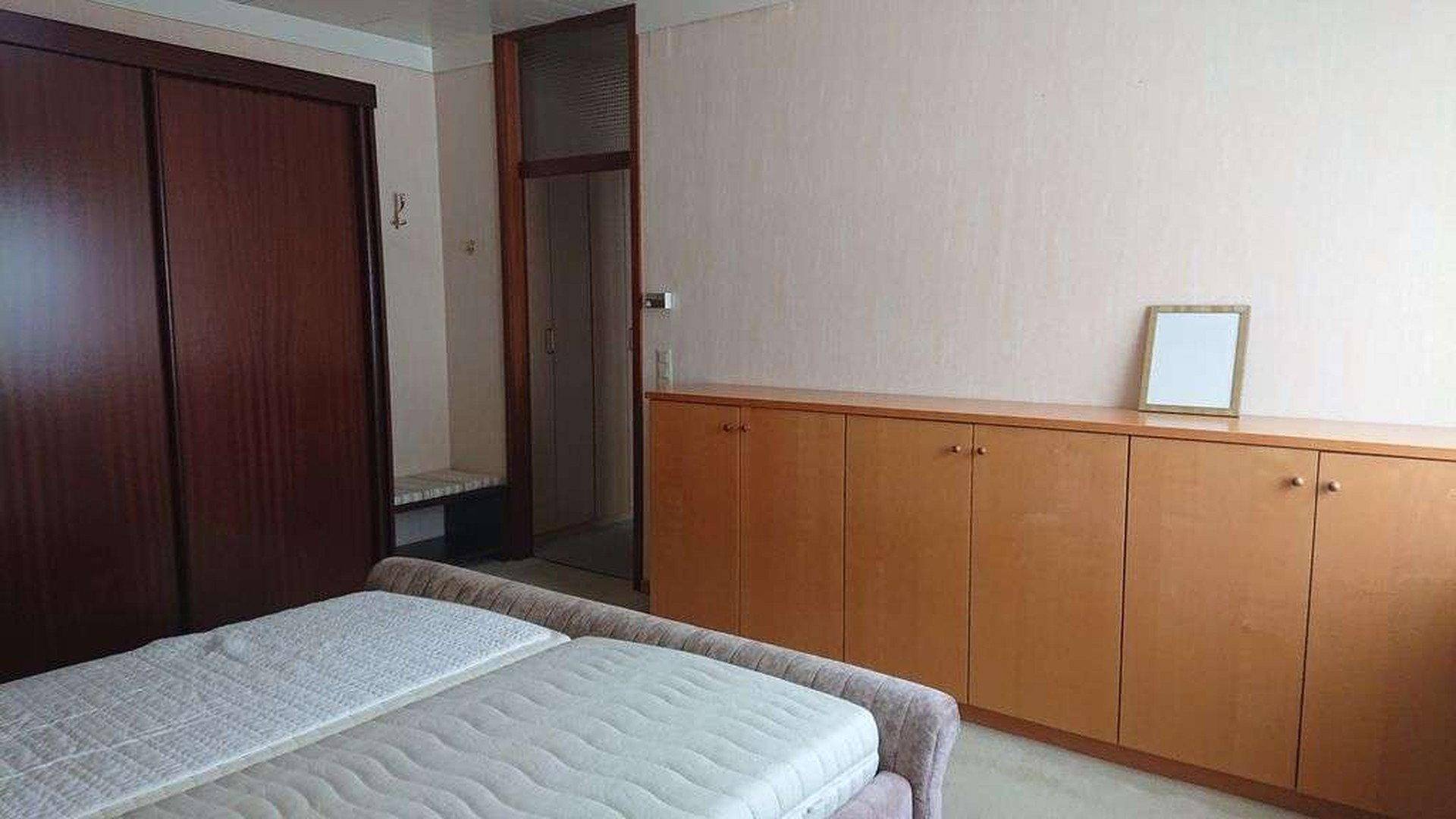 Schlafzimmer mit Doppelbett, Holzschränken und hellem Teppichboden.