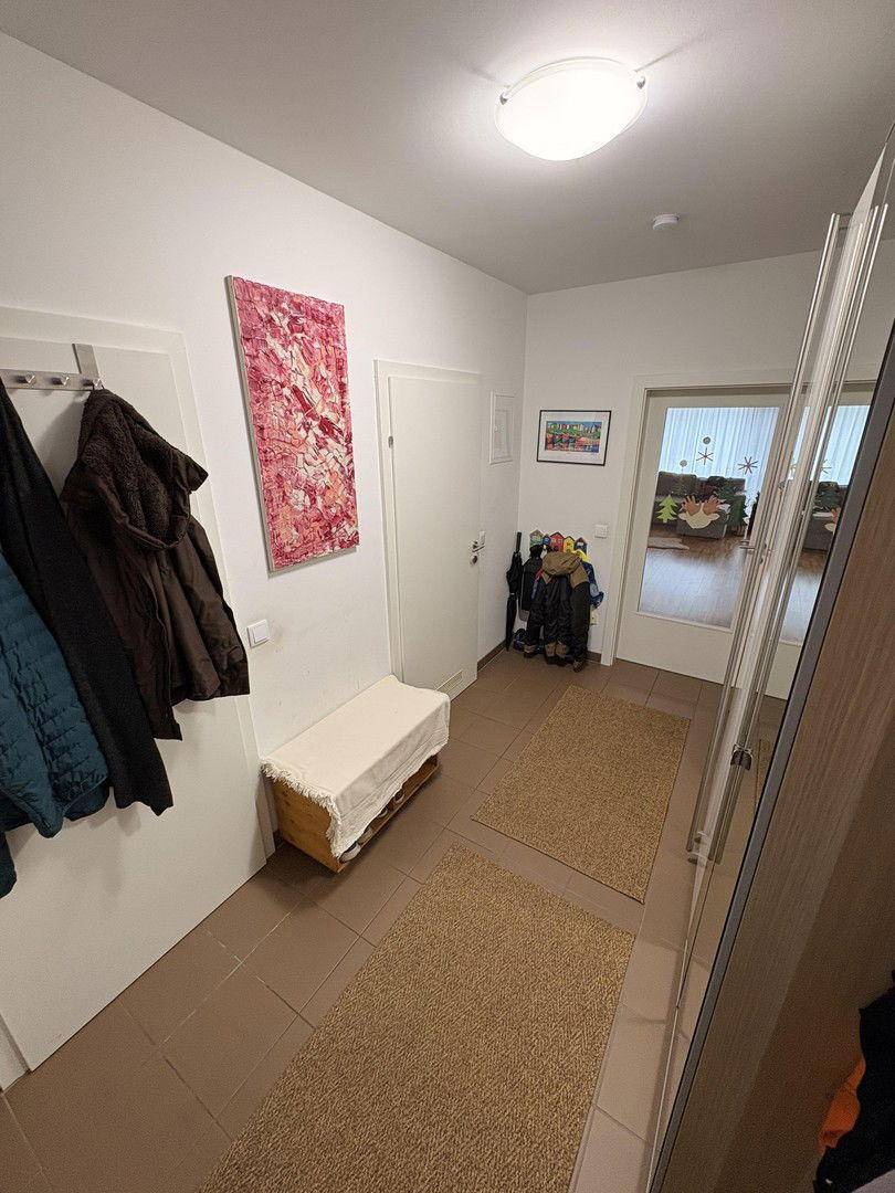 Eingangsbereich mit Fliesenboden, Garderobe und einem Spiegel, der den Raum optisch erweitert.