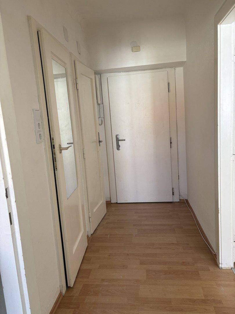 Heller Flur mit Holzfußboden und mehreren weißen Türen, eine davon mit integriertem Spiegel.