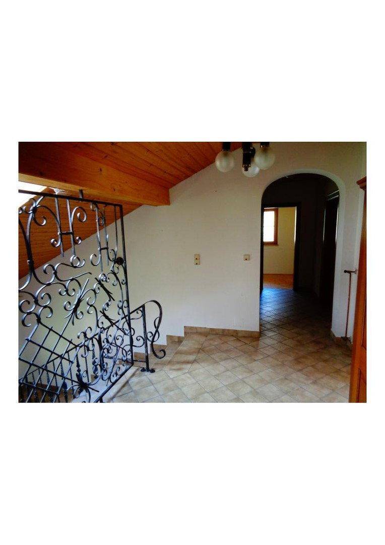 Heller Flur mit Fliesenboden, Treppe und Zugang zu weiteren Räumen im Obergeschoss des Hauses.
