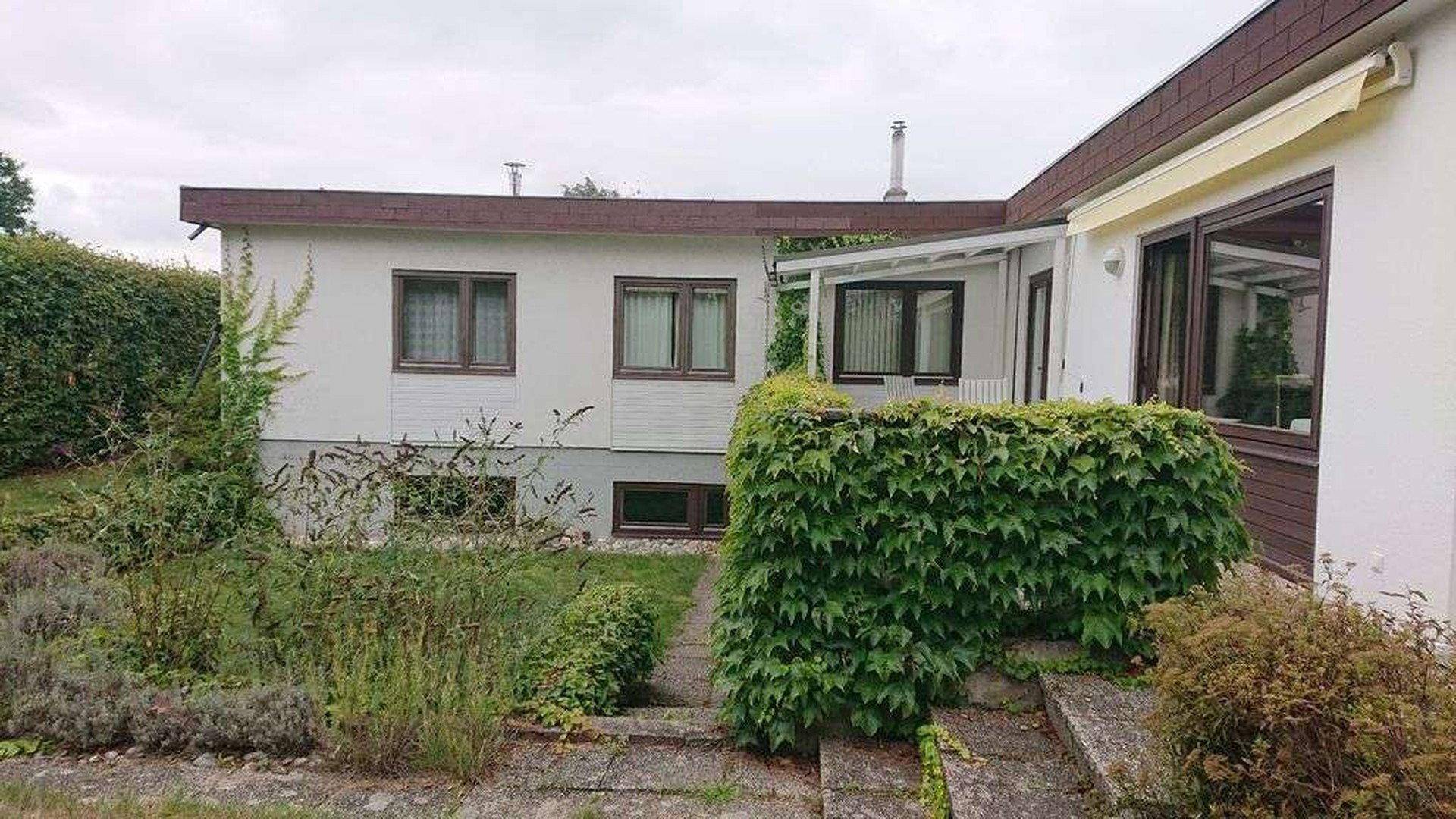 Gartenbereich mit gepflegtem Rasen, Hecken und dem Haus im Hintergrund.