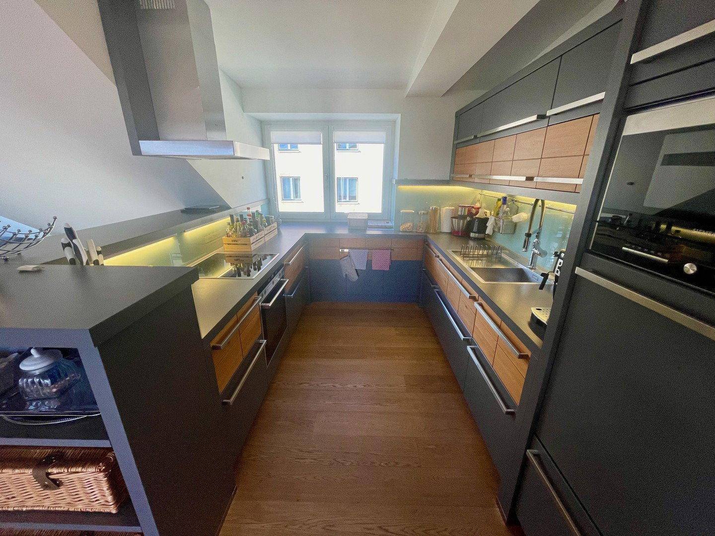 Moderne U-förmige Küche mit grauen Fronten, Holzakzenten und einem Fenster.