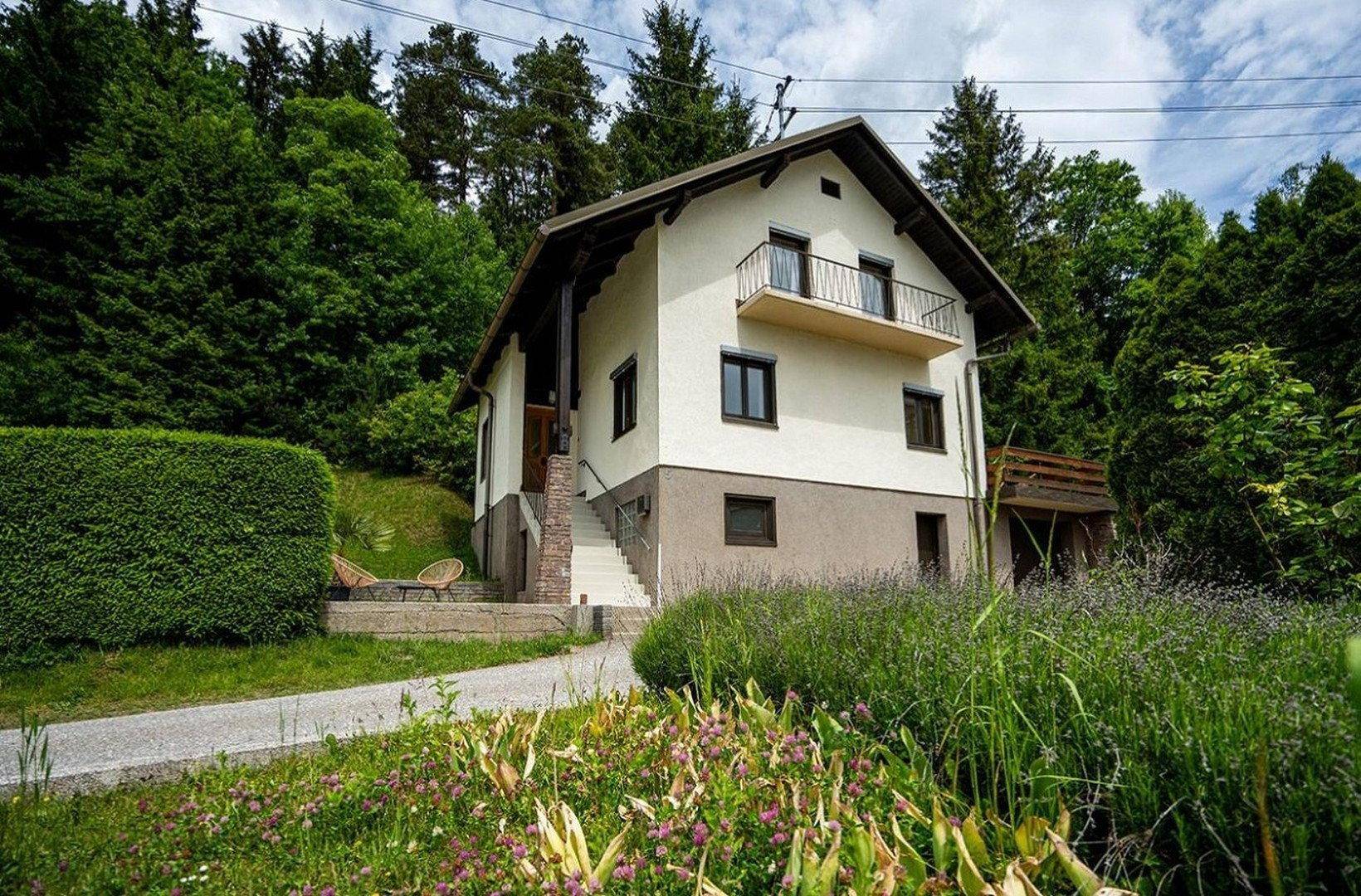 Freistehendes Haus in grüner Hanglage mit Balkon und Terrasse.