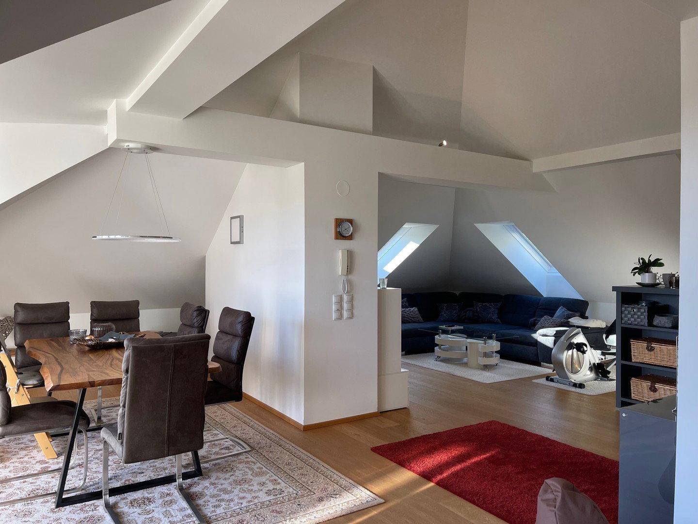 Geräumiger Wohn- und Essbereich mit Dachschrägen, Holzboden und viel Tageslicht.