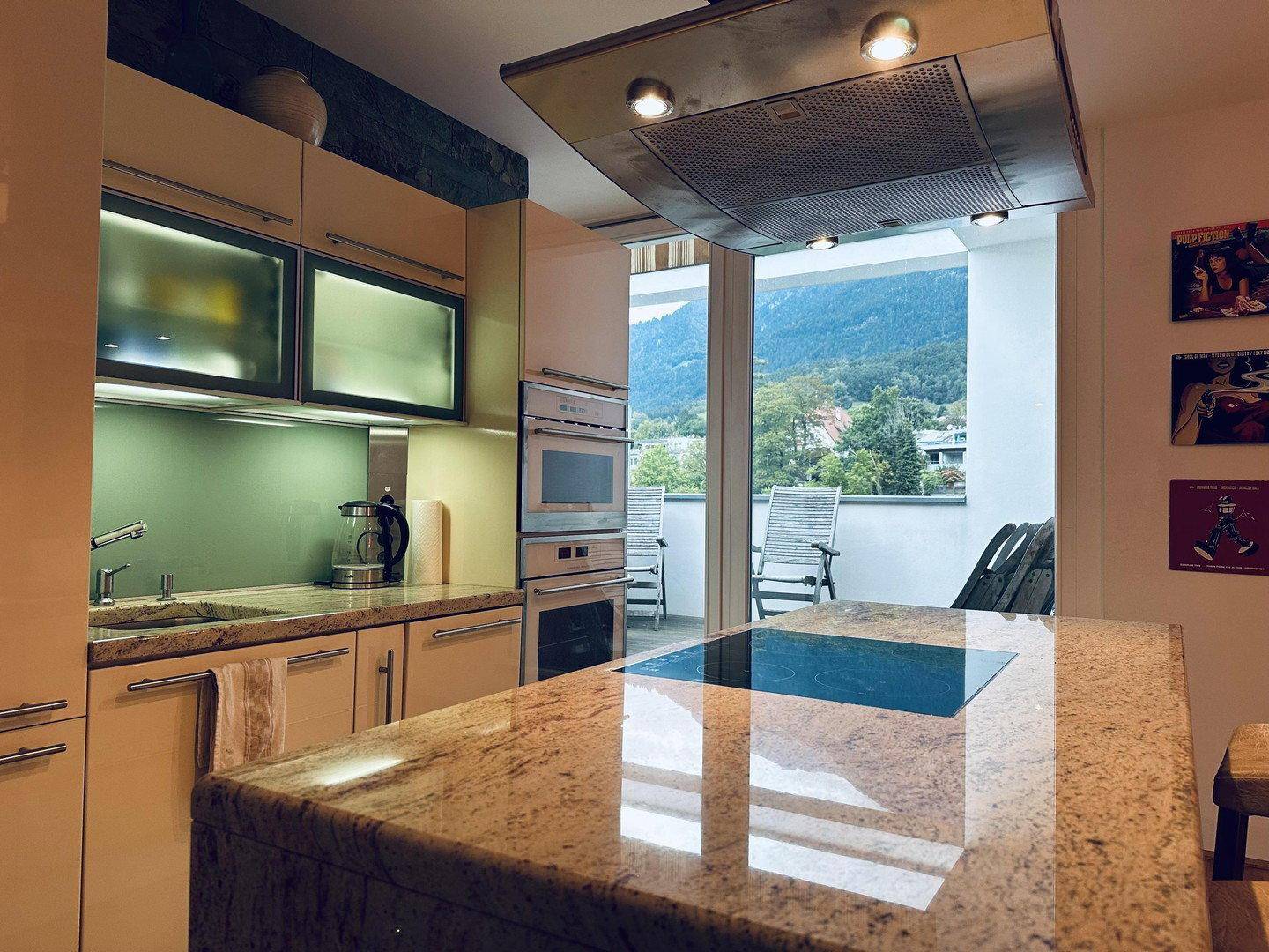 Moderne Küche mit Kochinsel, Granitarbeitsplatte und Blick auf die Berge von der Terrasse.