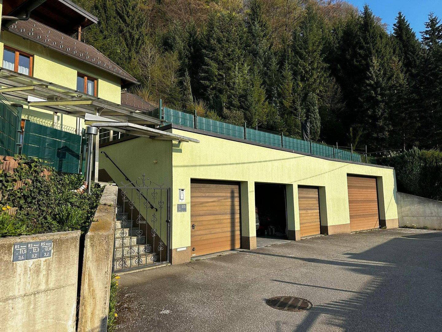 Mehrere Garagen mit Holztoren und Zufahrt, integriert in die Hanglage des Grundstücks.