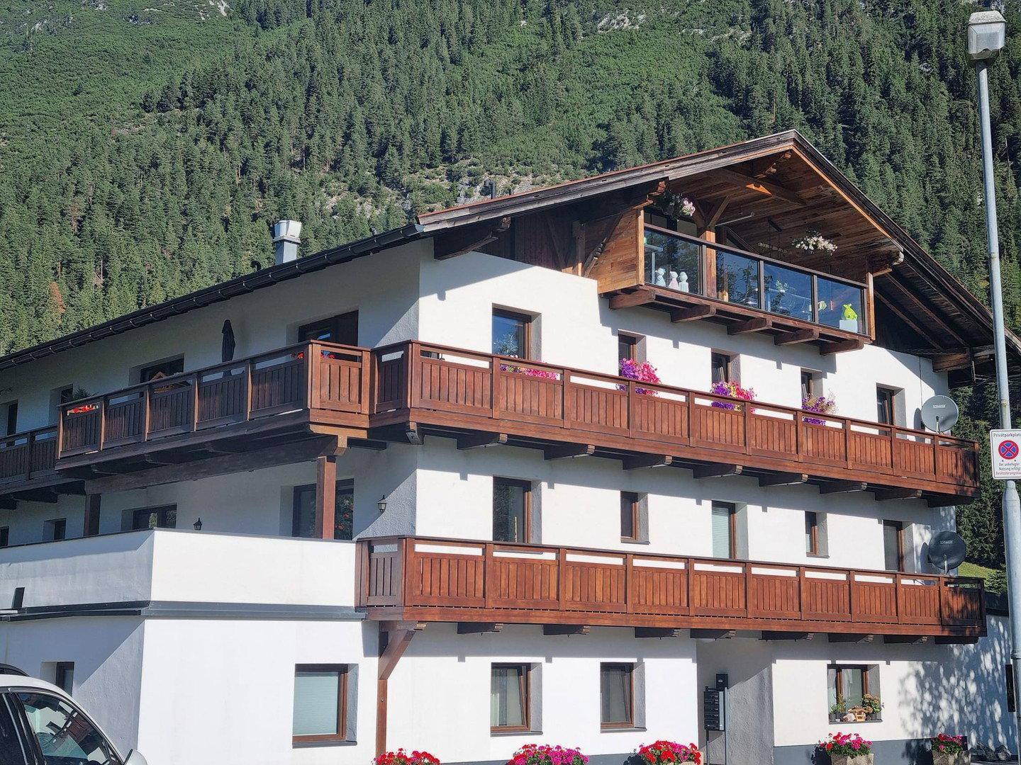 Traditionelles Gebäude mit Holzbalkonen und Blick auf die umliegenden Berge und Wälder.