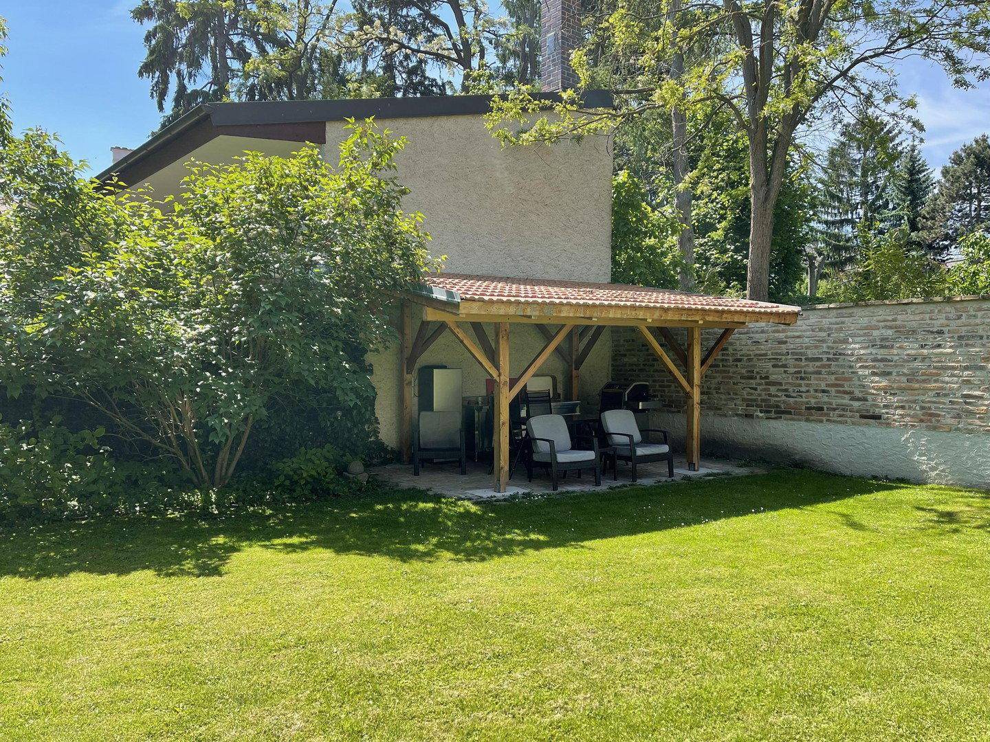 Gartenbereich mit Holzpergola und Sitzgelegenheiten im Freien.