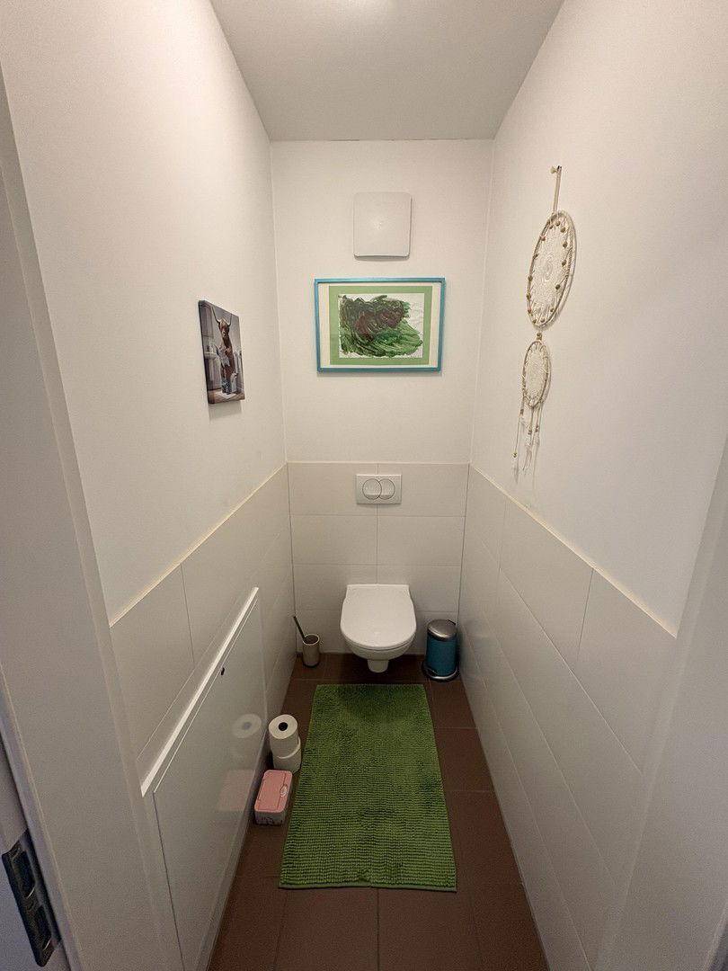 Kleines Gäste-WC mit Wand-WC, Fliesenboden und einem Abluftventilator.