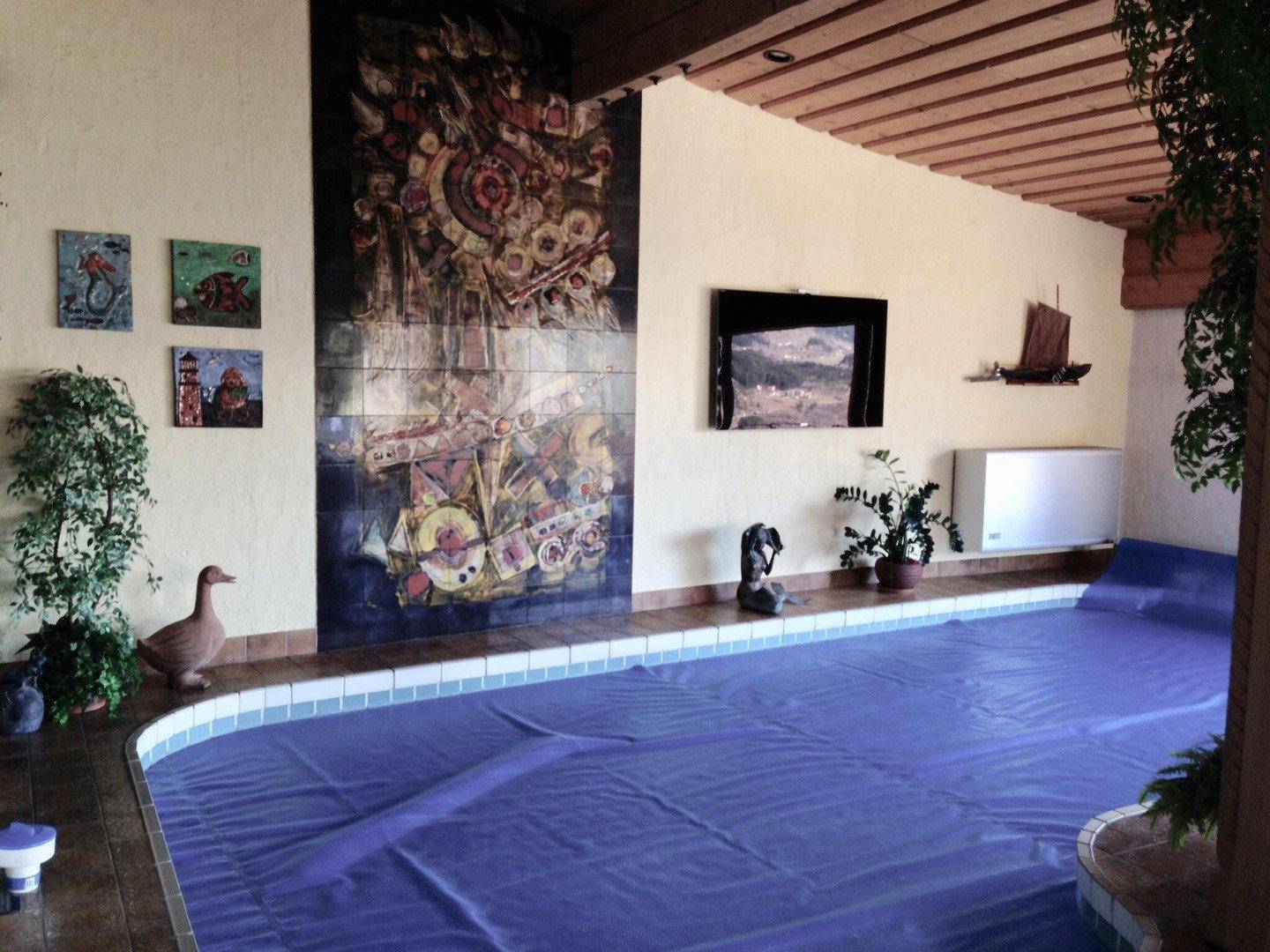 Innenpoolbereich mit dekorativer Wandkunst und Holzdecke, ideal für Entspannung und Sport.