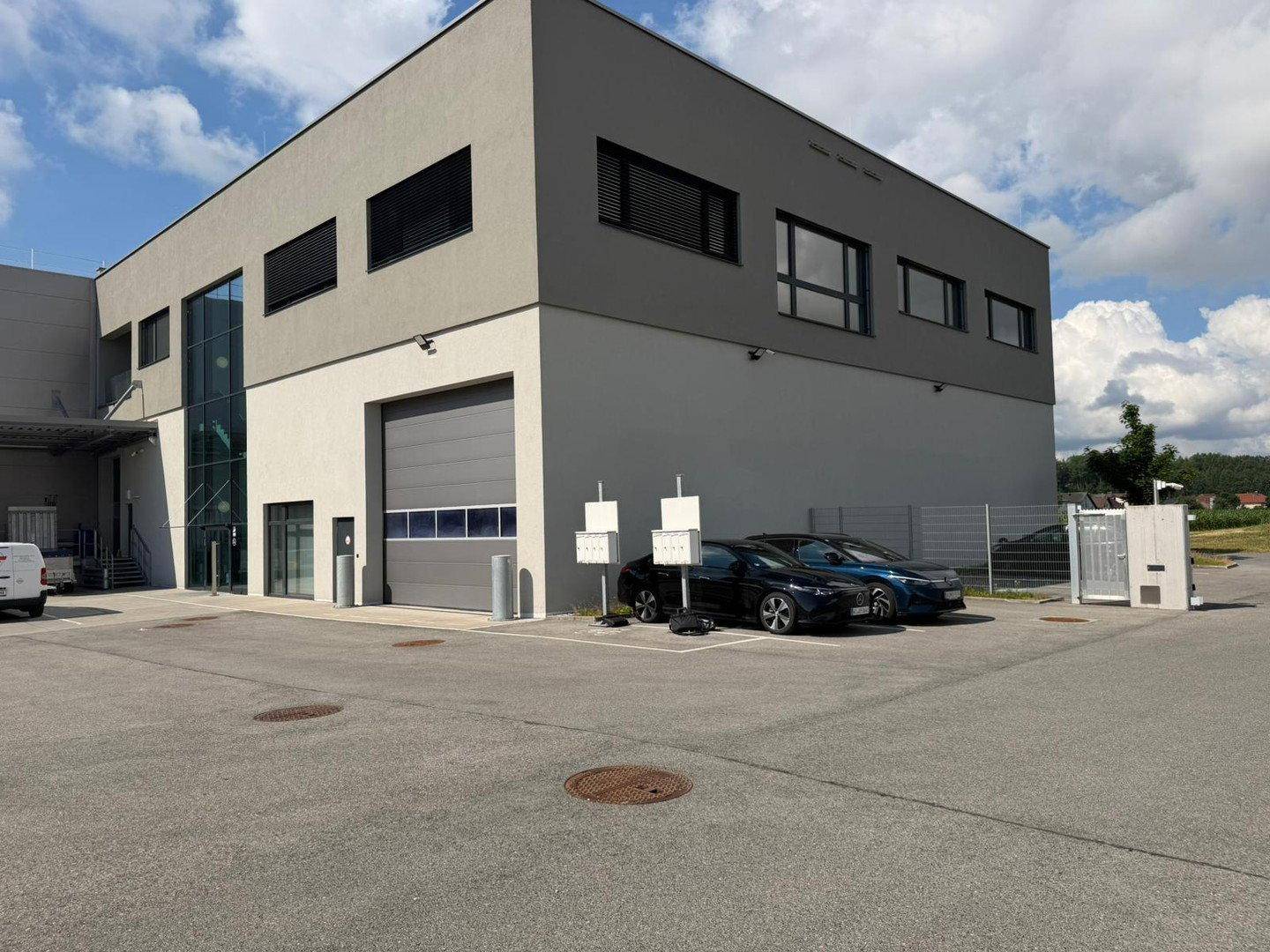 Außenansicht eines modernen Geschäftsgebäudes mit Parkplätzen und Laderampe.