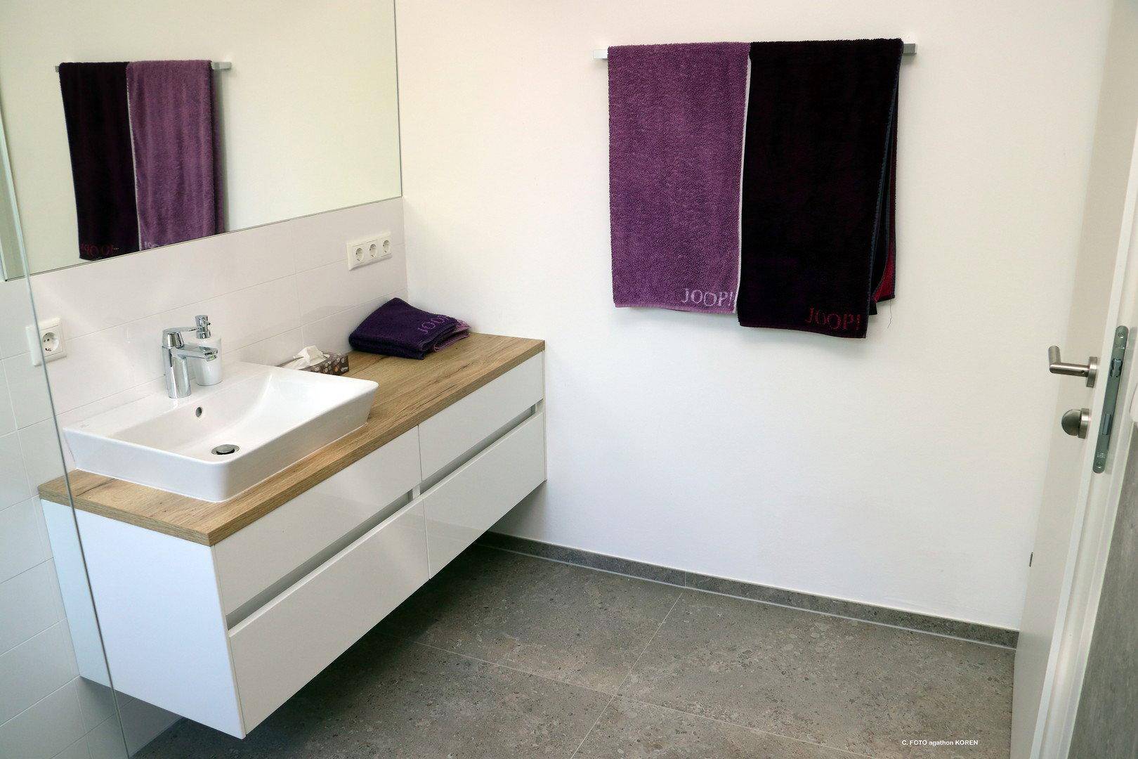Modernes Badezimmer mit schwebendem Waschtisch, Einzelwaschbecken und großem Spiegel.