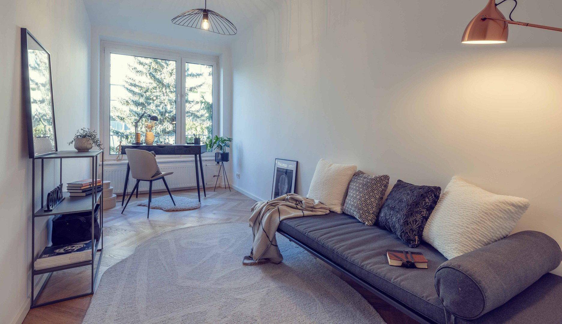 Helles Arbeitszimmer mit Schreibtisch, Tagesbett und großem Fenster mit Blick ins Grüne.
