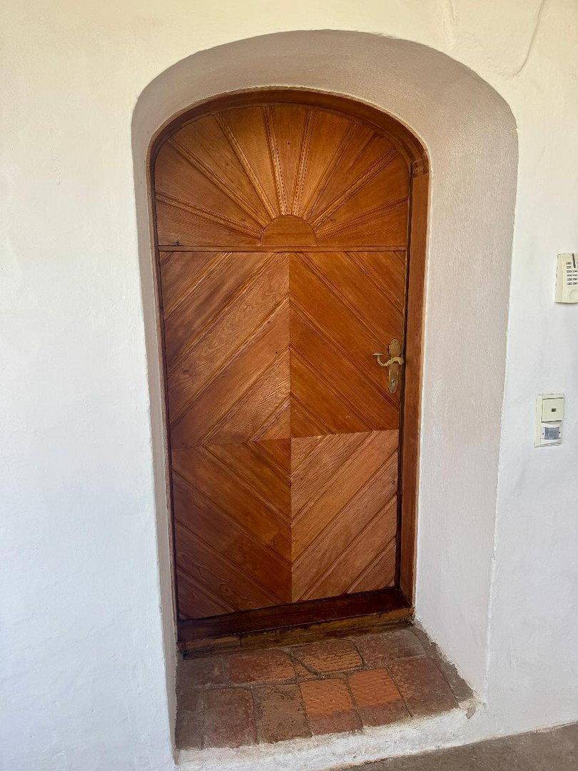 Rustikale Holztür in einem gewölbten Durchgang mit traditionellem Design.