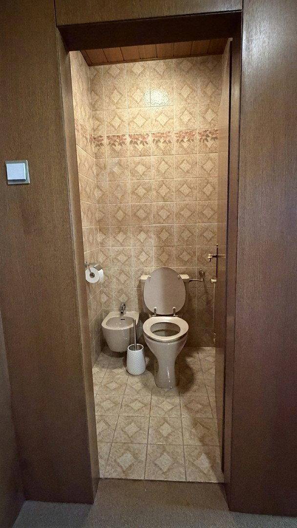 Separate Toilette mit Bidet und Fliesen im traditionellen Stil der 80er Jahre.