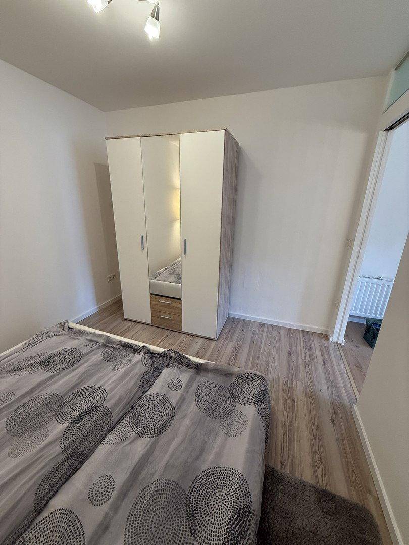 Schlafzimmer mit modernem Kleiderschrank und Zugang zu einem weiteren Raum.