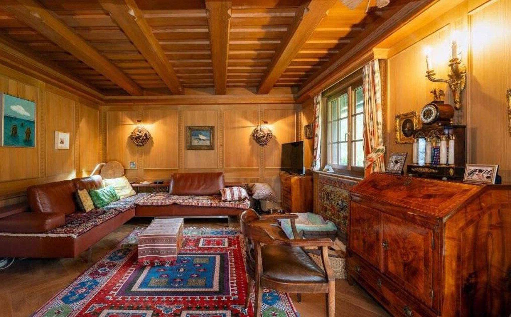 Traditionelles Wohnzimmer mit Holztäfelung, sichtbaren Deckenbalken und bequemen Ledersofas.