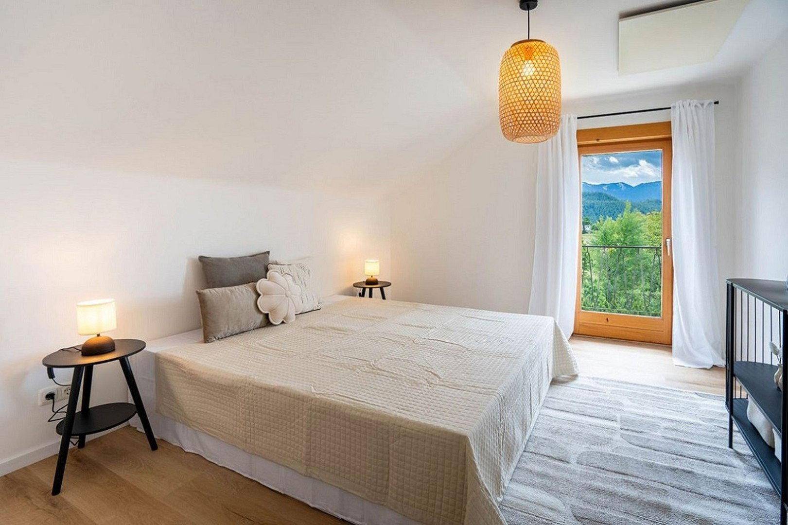 Schlafzimmer mit Doppelbett, Holzboden und Zugang zu einem französischen Balkon mit Bergblick.