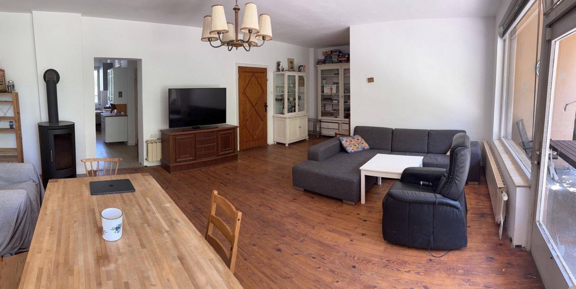 Geräumiger Wohn- und Essbereich mit Holzboden, Kaminofen und Zugang zum Außenbereich.