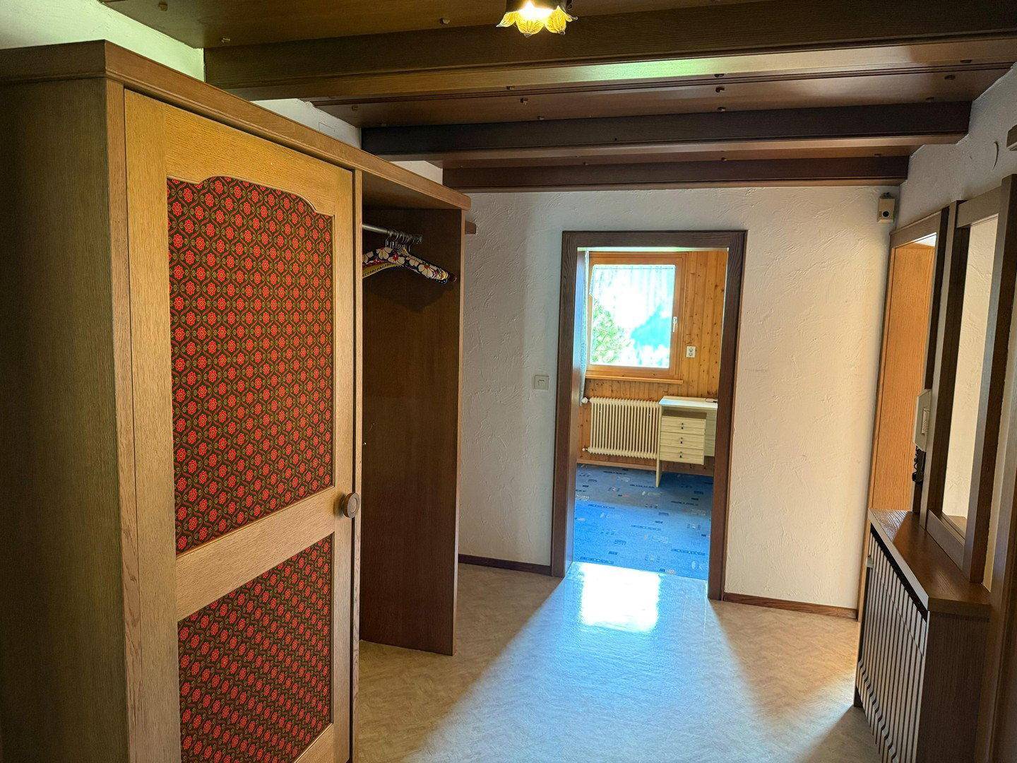 Flur mit Holzbalkendecke, Einbauschrank und Zugang zu weiteren Zimmern.