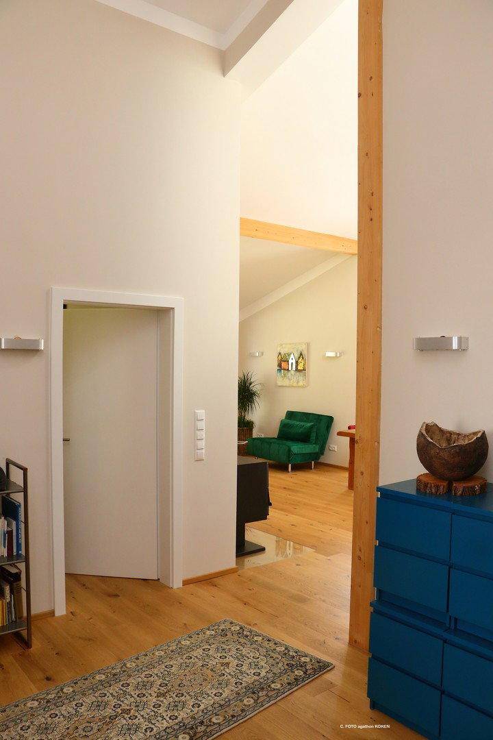 Heller Flur mit Holzboden, hohen Decken und Blick in den offenen Wohnbereich.