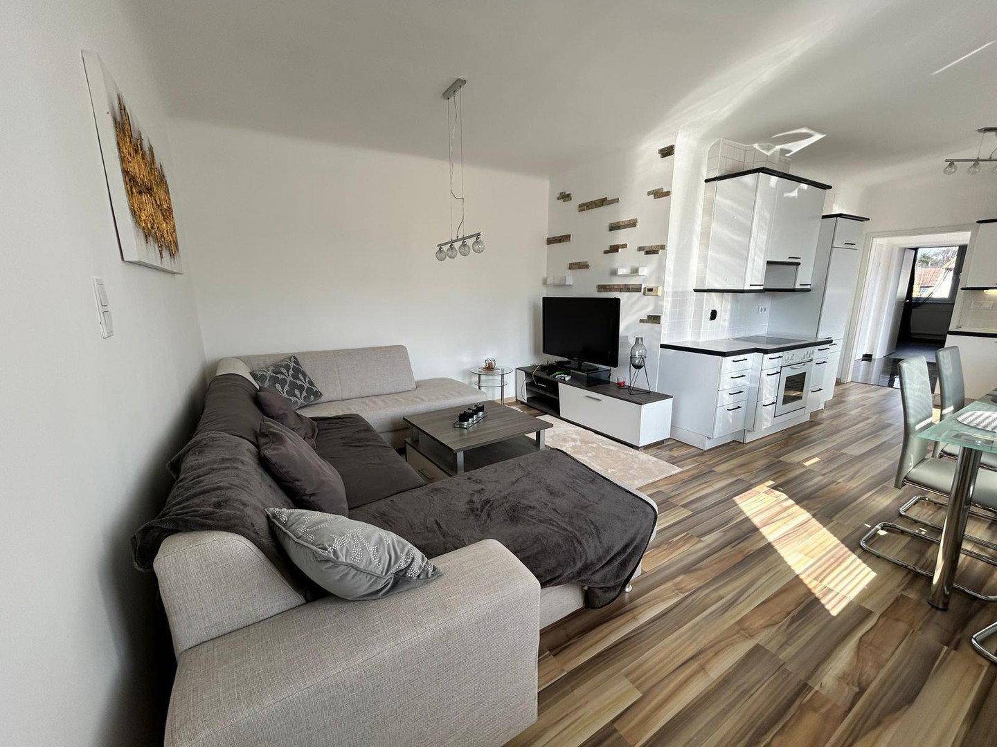 Gemütlicher Wohnbereich mit großem Sofa, Couchtisch und Fernseher, offen zur Küche.