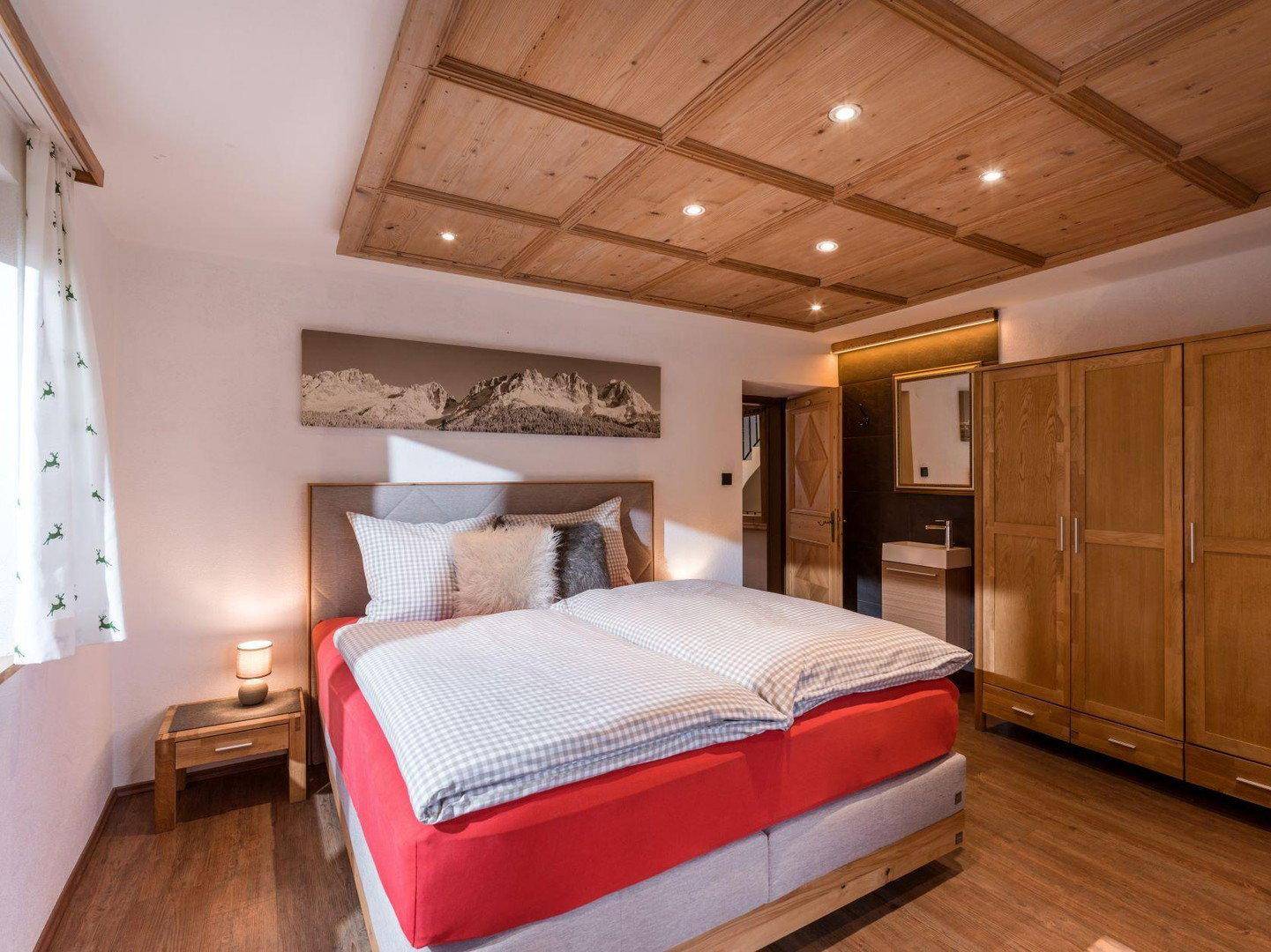 Schlafzimmer mit Holzkassettendecke, Doppelbett und Einbauschränken.