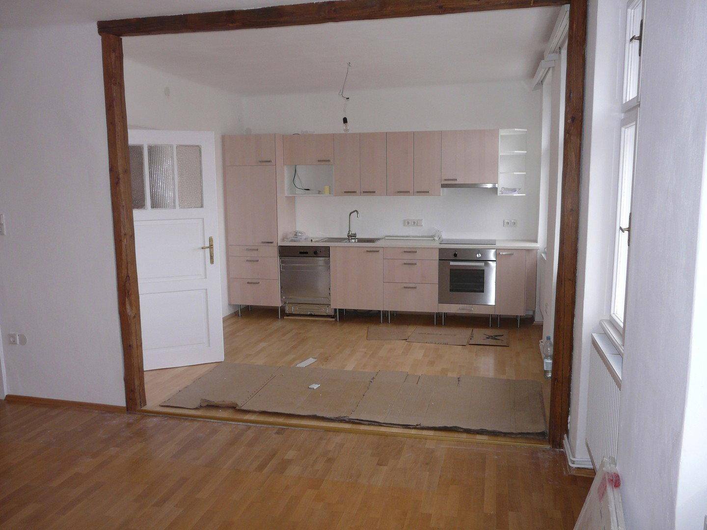 Neu installierte Küche mit hellen Schränken und integrierten Geräten, offen zum Wohnbereich.