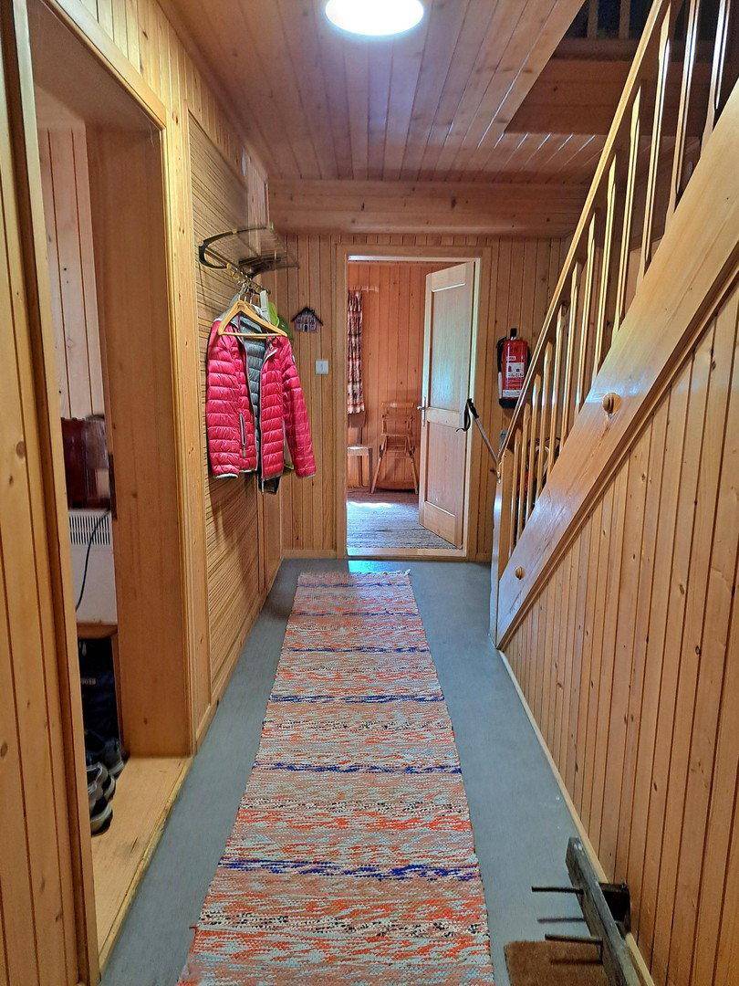 Rustikaler Flur mit Holzvertäfelung und Treppe, die zu den oberen Etagen führt.