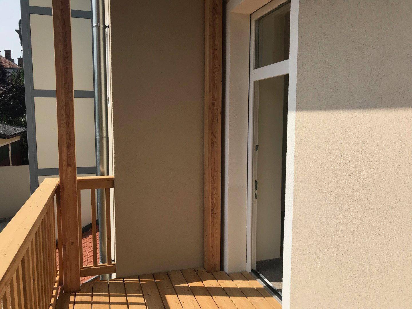 Heller Balkon mit Holzfußboden und Holzgeländer, ideal für entspannte Stunden im Freien.