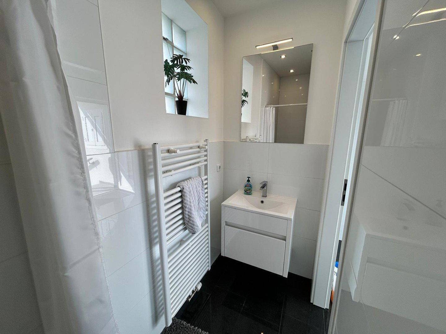 Modernes Badezimmer mit Waschtisch, Spiegel, beheiztem Handtuchhalter und Glasbausteinfenster.