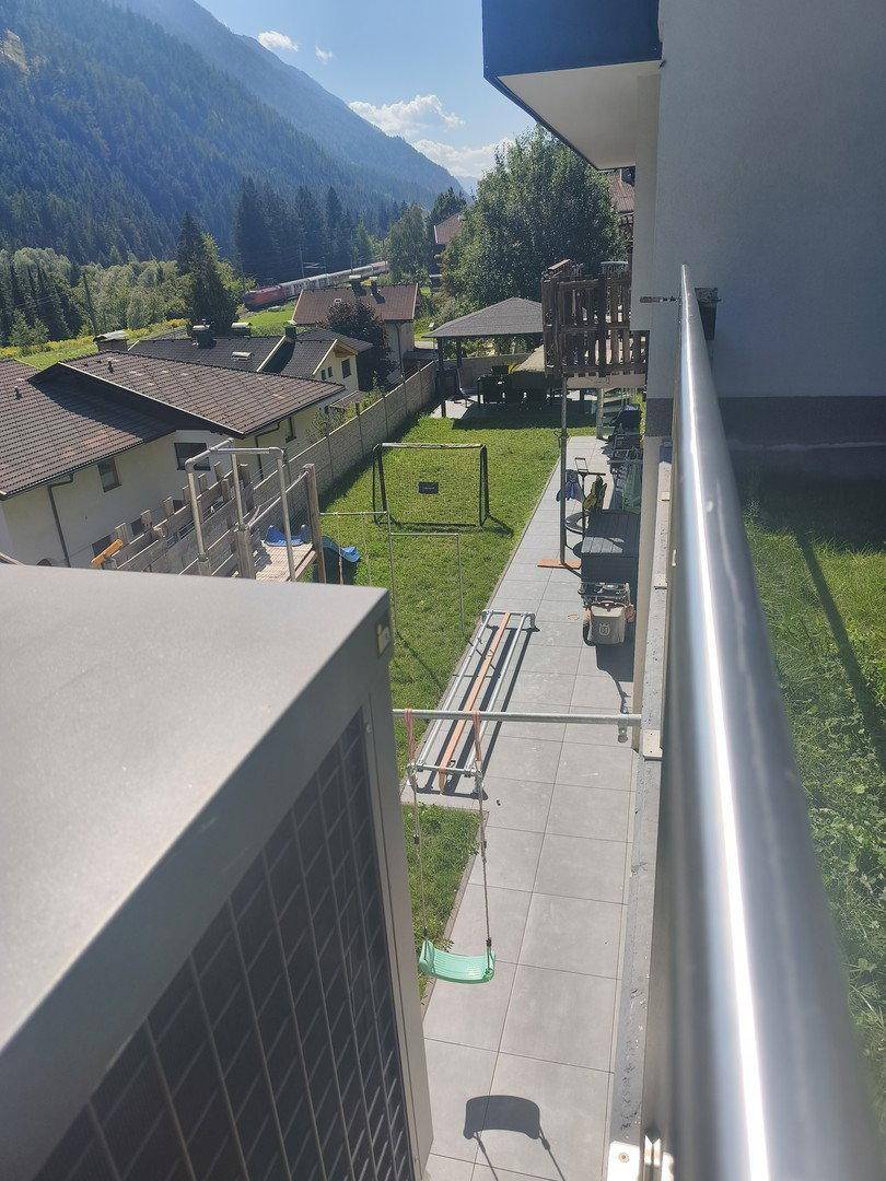 Blick von oben auf einen gepflegten Gartenbereich mit Rasenfläche und Kinderspielgeräten.