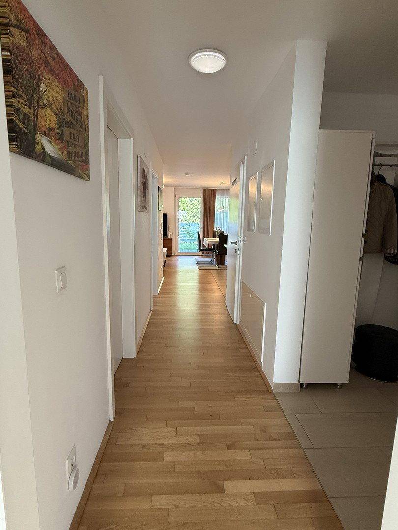 Langer, heller Flur mit Holzboden, der zu den Wohnbereichen und dem Garten führt.